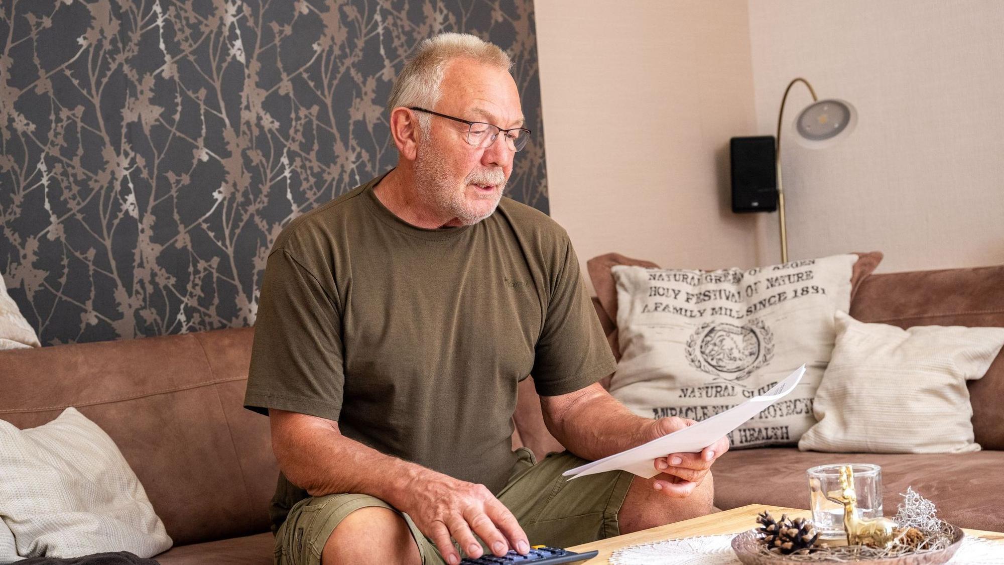 Ein älterer Mann guckt mit Taschenrechner durch Unterlagen