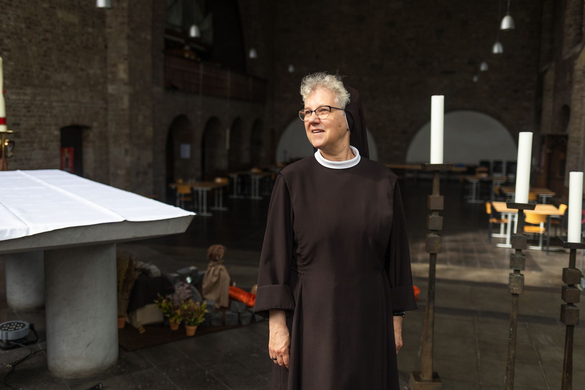 Eine Frau in schwarzer Nonnenkleidung steht in einer Kirche.