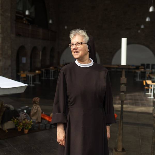 Eine Frau in schwarzer Nonnenkleidung steht in einer Kirche.