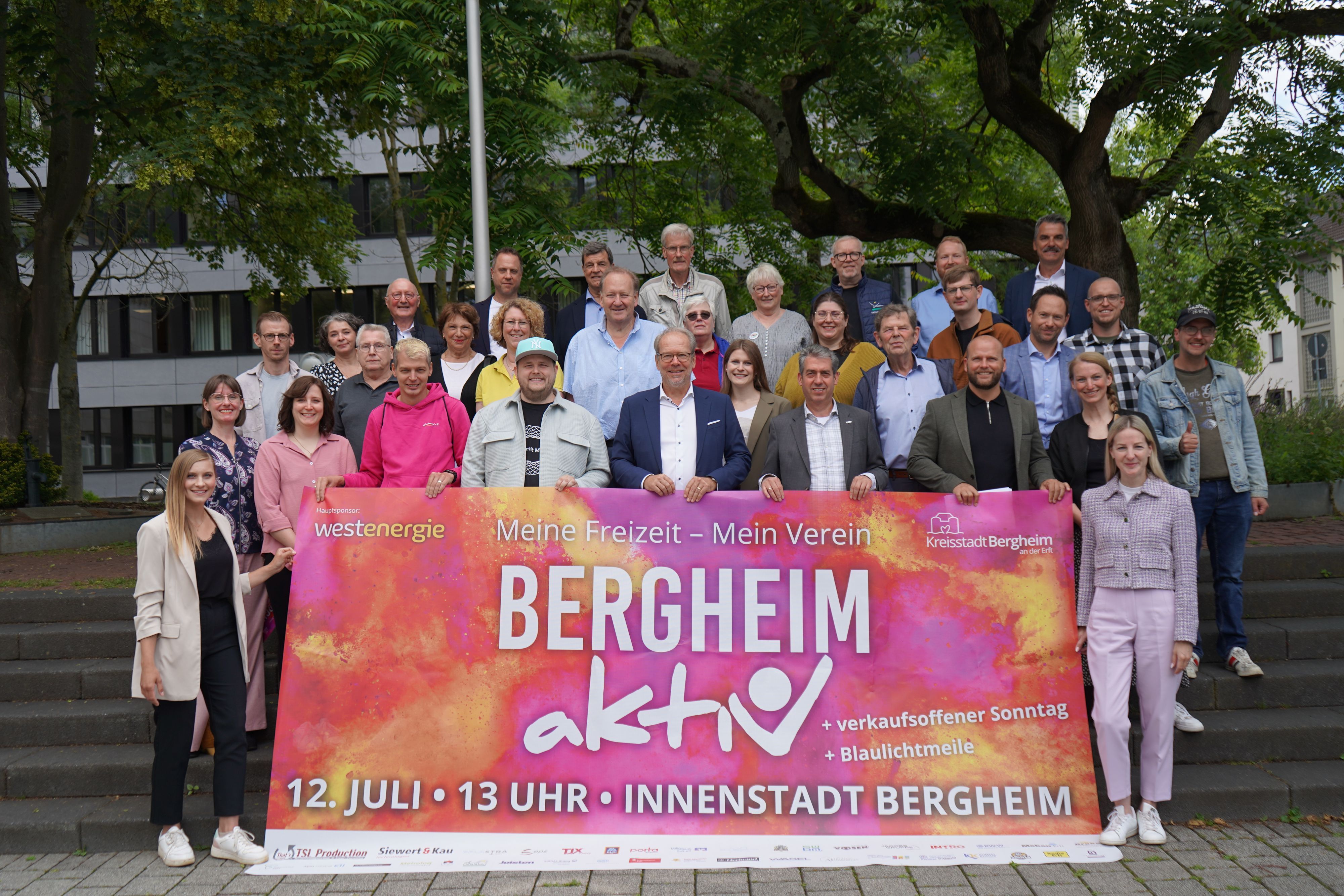 Das Bild zeigt ein Banner mit der Aufschrift „Bergheim aktiv“. Vertreter der Verwaltung sowie der vielen Vereine und Sponsoren haben sich zu einem Gruppenbild versammelt.