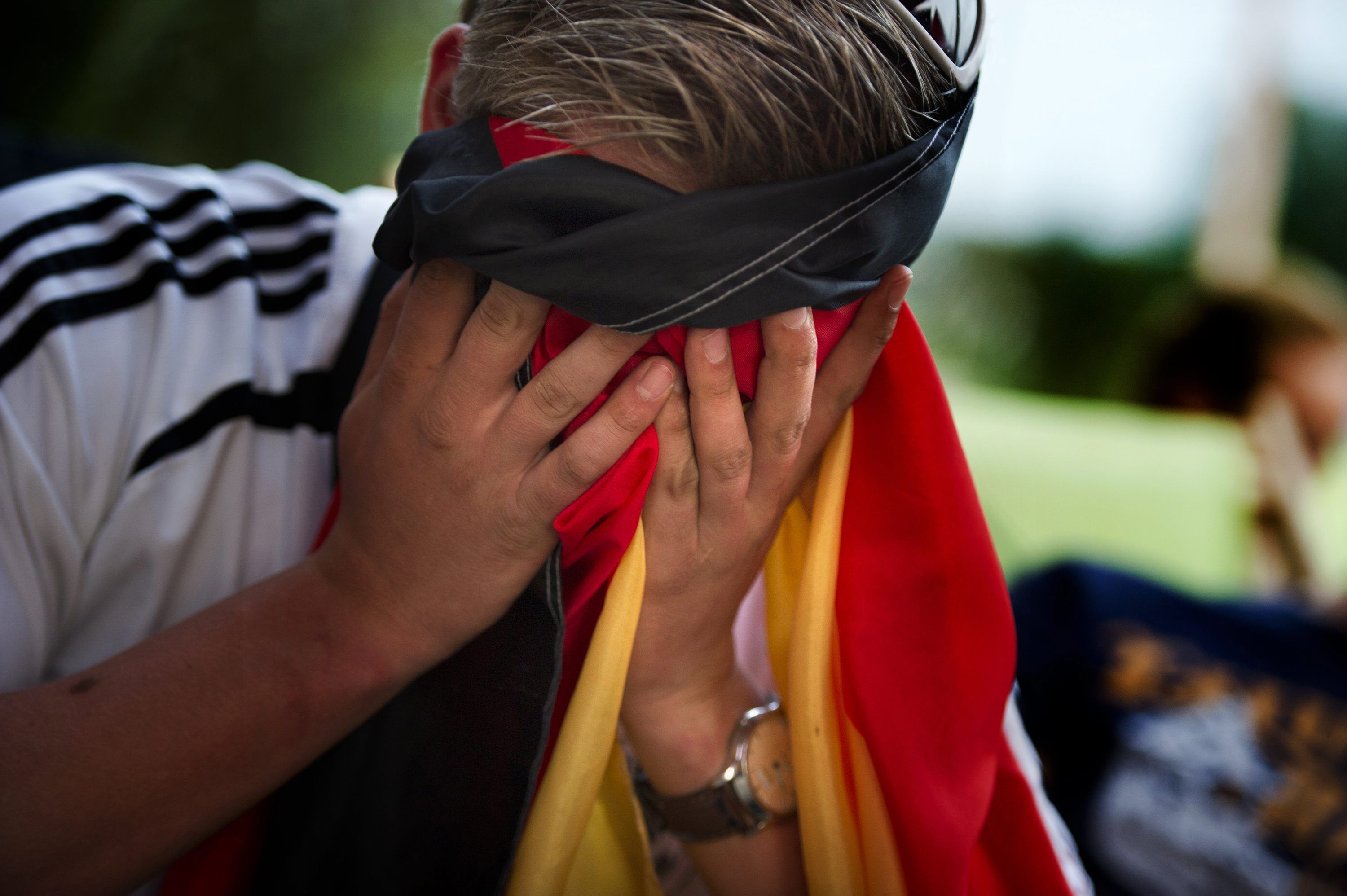 Ein Fußballfan hält sich seine Fahne vors Gesicht.