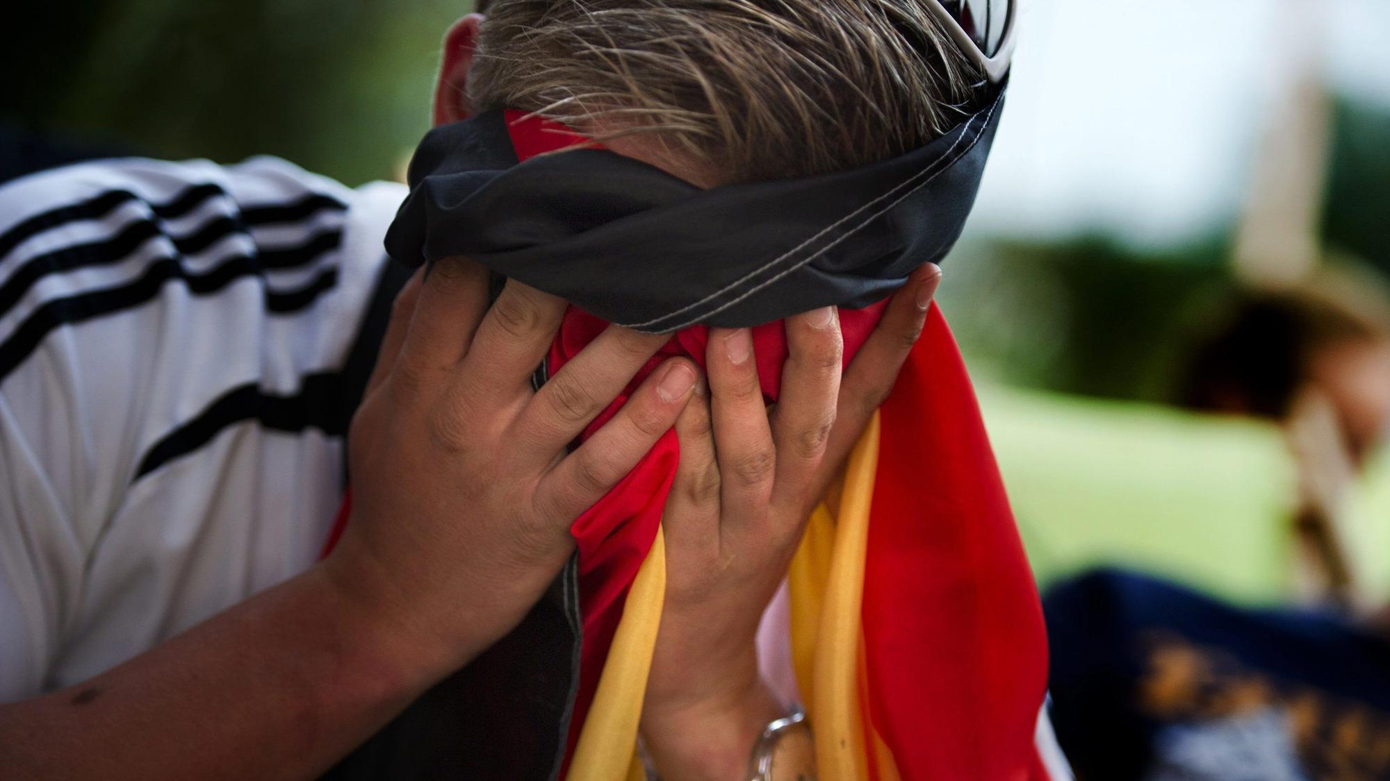 Ein Fußballfan hält sich seine Fahne vors Gesicht.