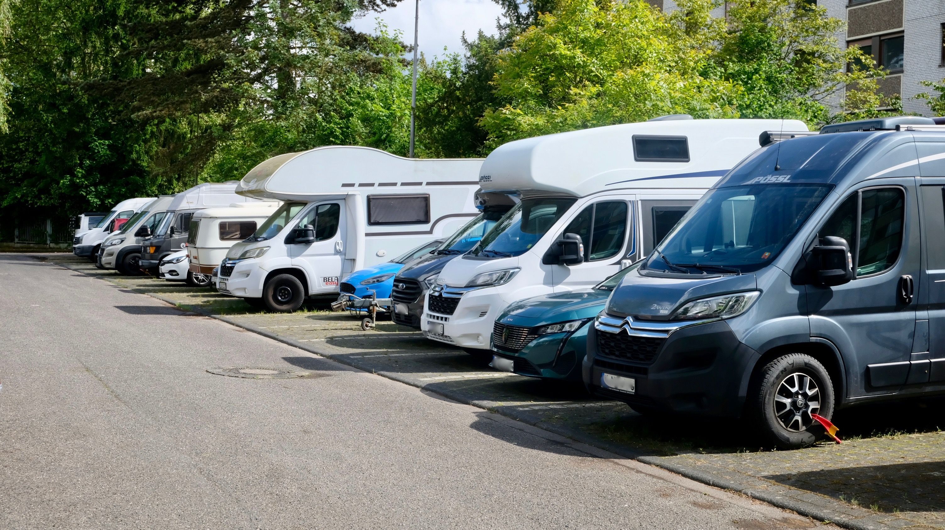 Viele Wohnmobile stehen auf einem Parkplatz nebeneinander.