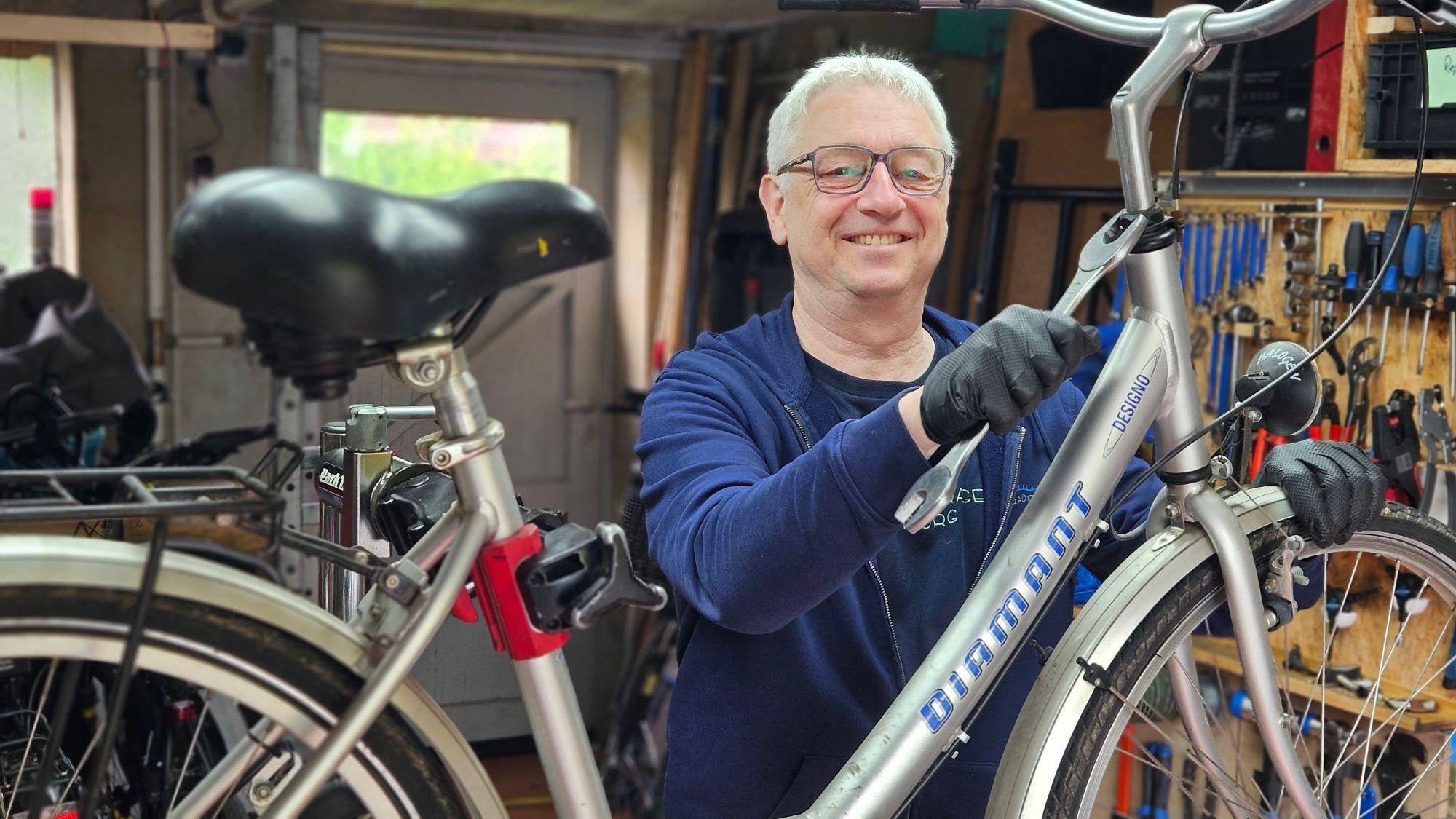 Zu sehen ist Frank Büttgen, der in seiner Garage an einem Fahrrad arbeitet.