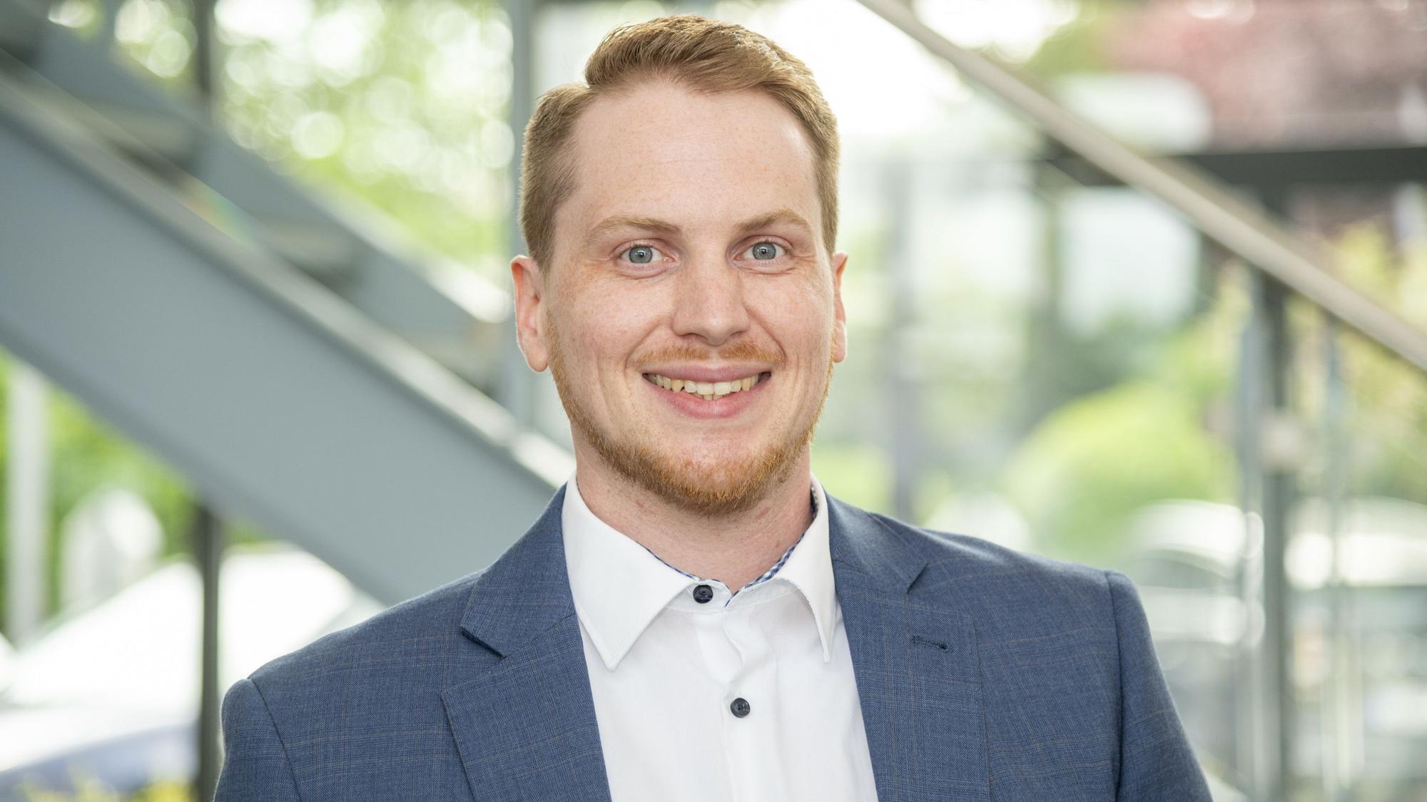 Ein Mann mit blondem Haar und Bart lächelt in die Kamera.