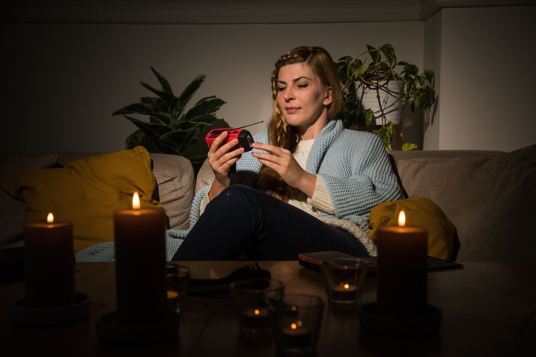 Eine Frau mit Kerzen während eines Stromausfalls auf dem Sofa