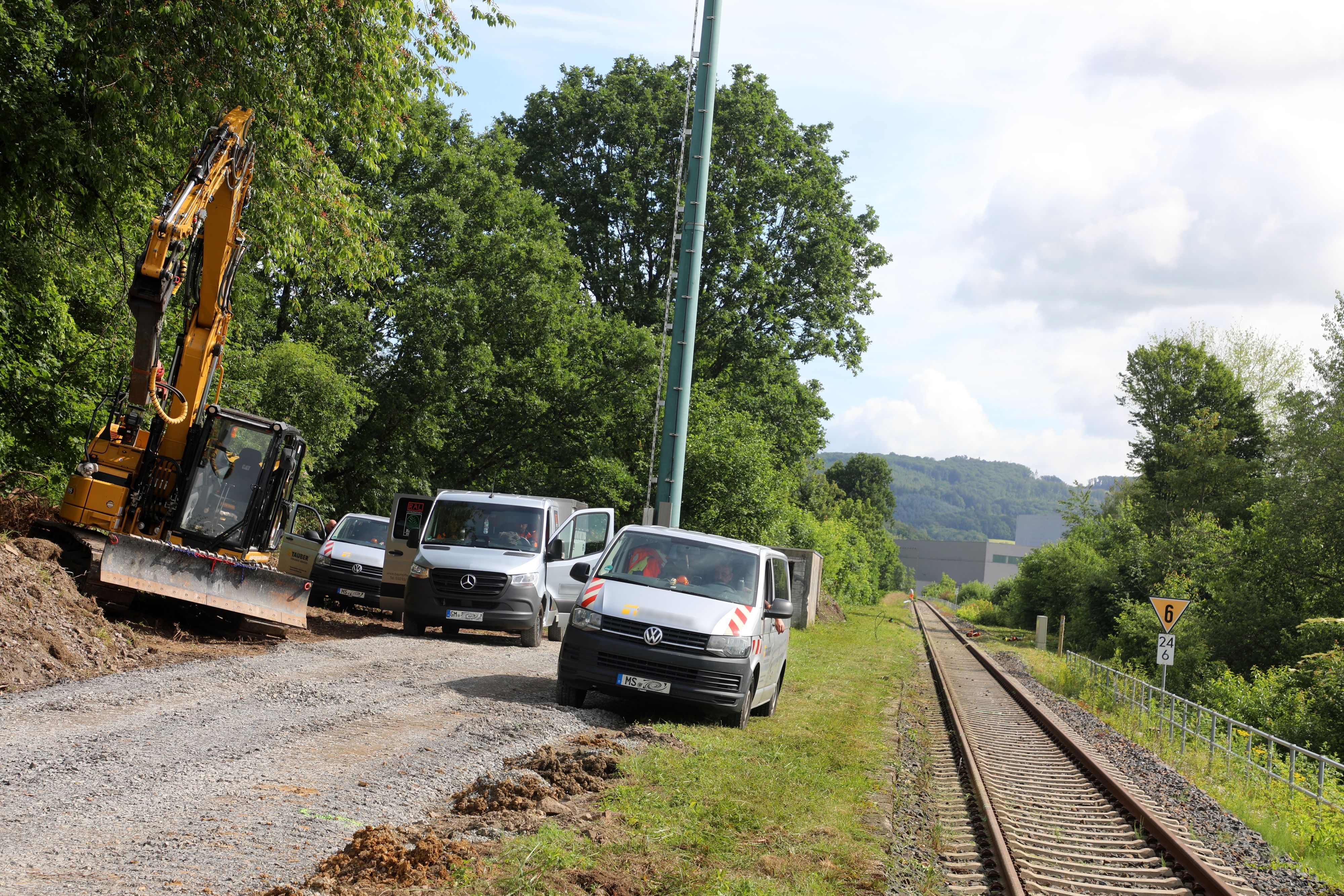 Baufahrzeuge und ein Bagger stehen neben einem frisch geschotterten Weg an der Regionalbahnstrecke 25 in Overath-Vilkerath.