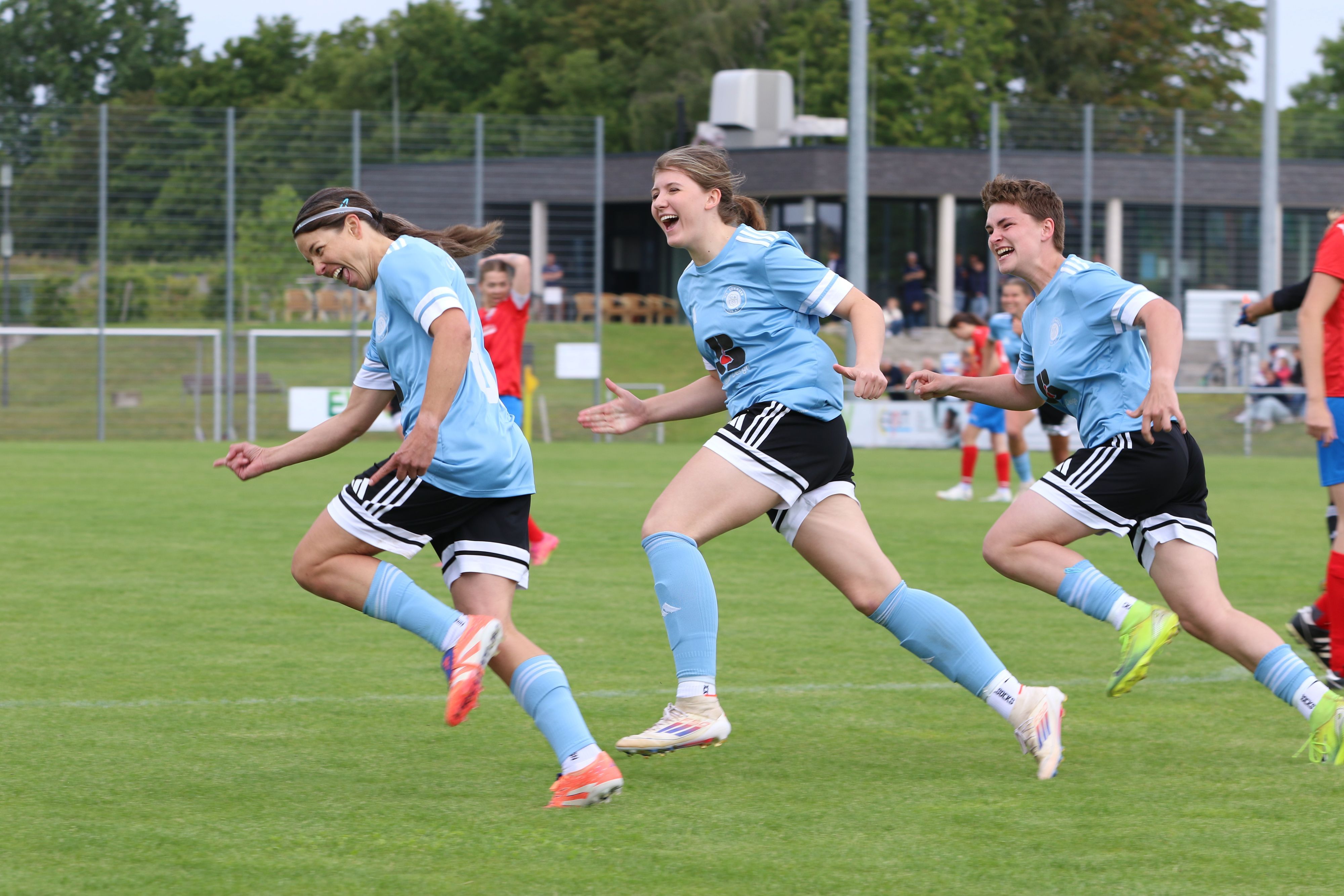 Drei Fußballerinnen freuen sich über ein Tor.