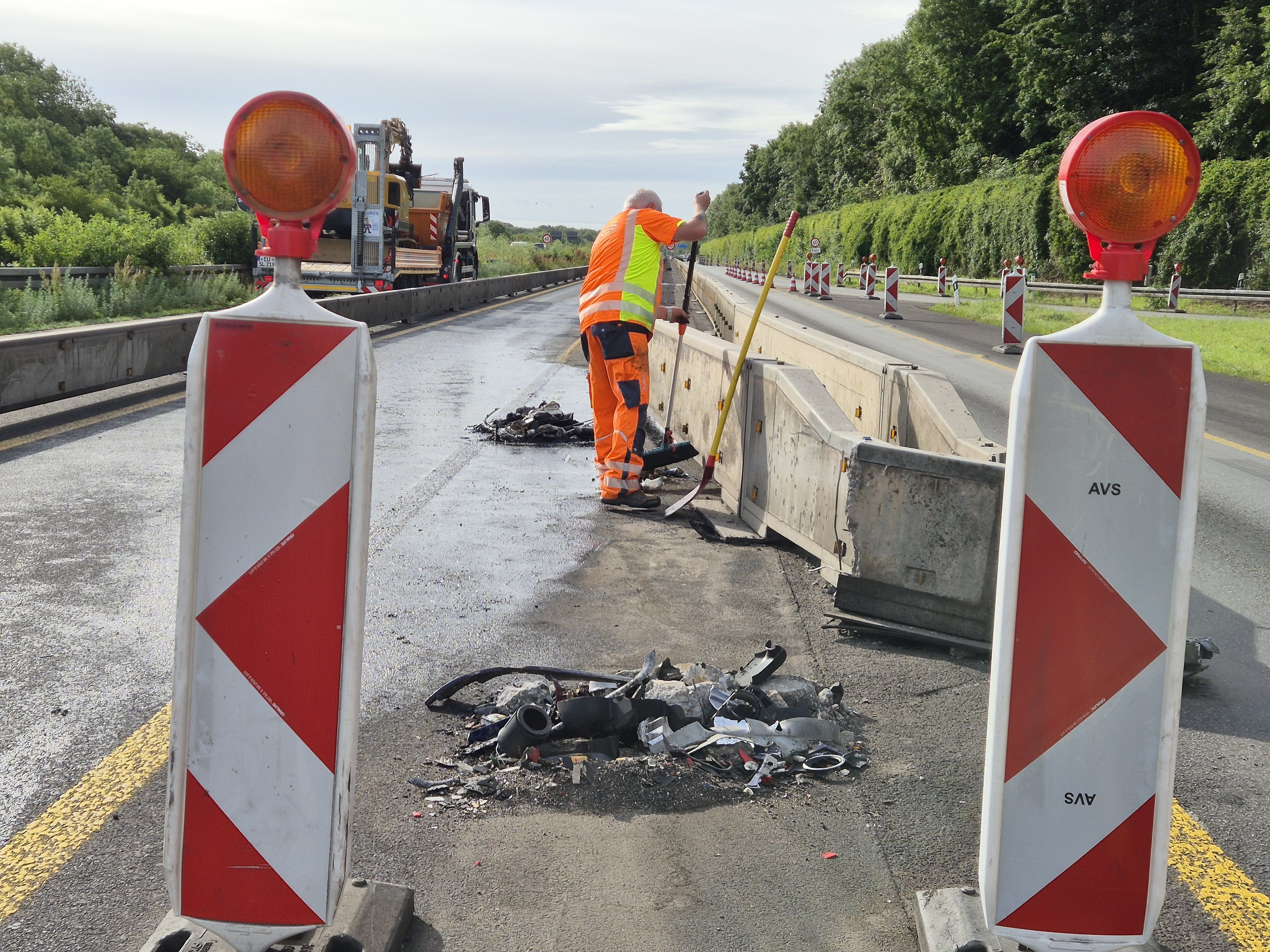 Ein Mitarbeiter kehrt Trümmerteile an der Baustelle zusammen. Nach einem nächtlichen Lkw-Unfall bei Köln-Klettenberg war die Autobahn 4 in Richtung Oberhausen am Morgen bis zum Kreuz Köln-West voll gesperrt.