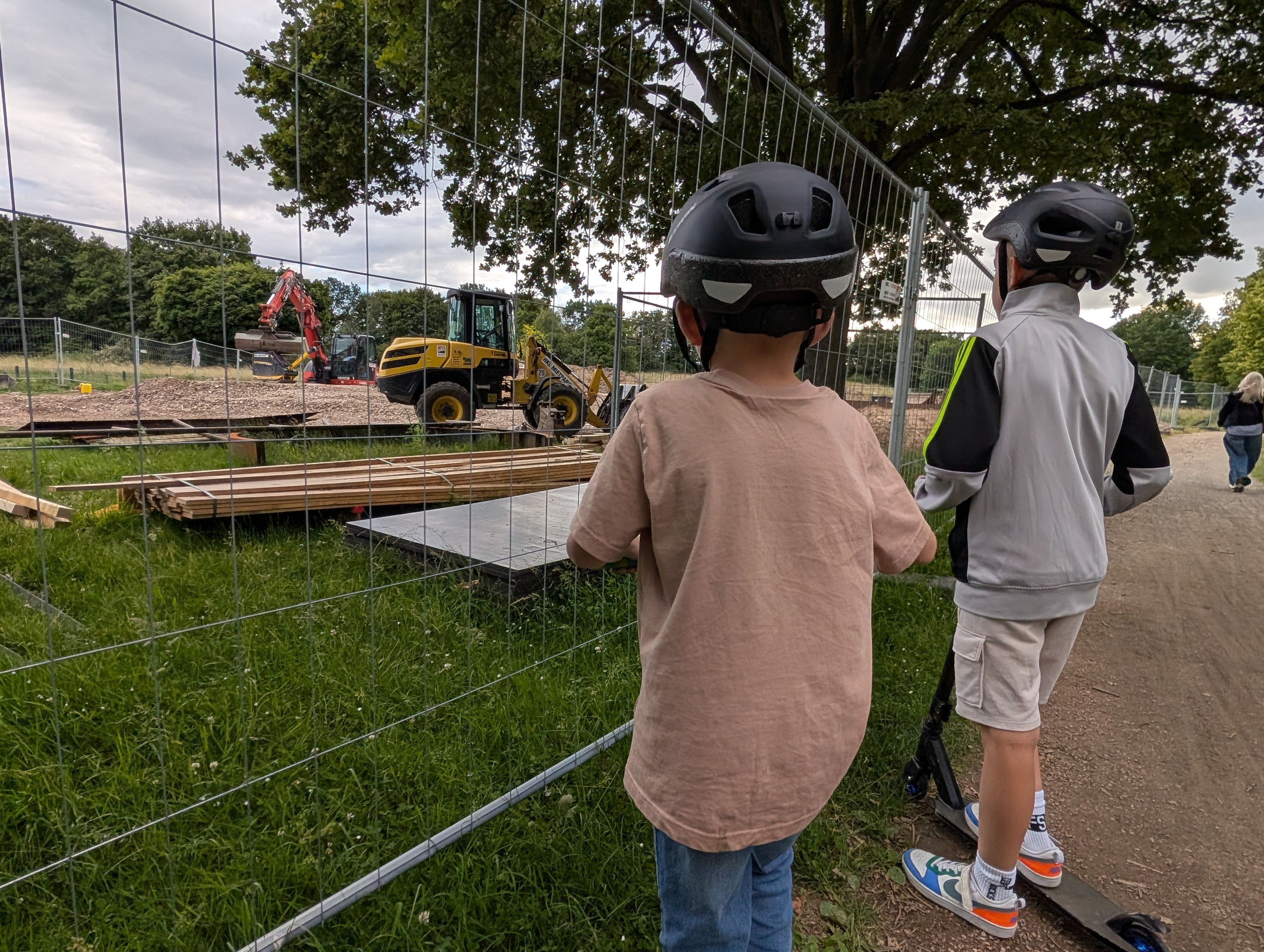 Das Foto zeigt zwei Jungen, die durch den Bauzaun auf die Baustelle der Skateanlage im Bürgerpark schauen.