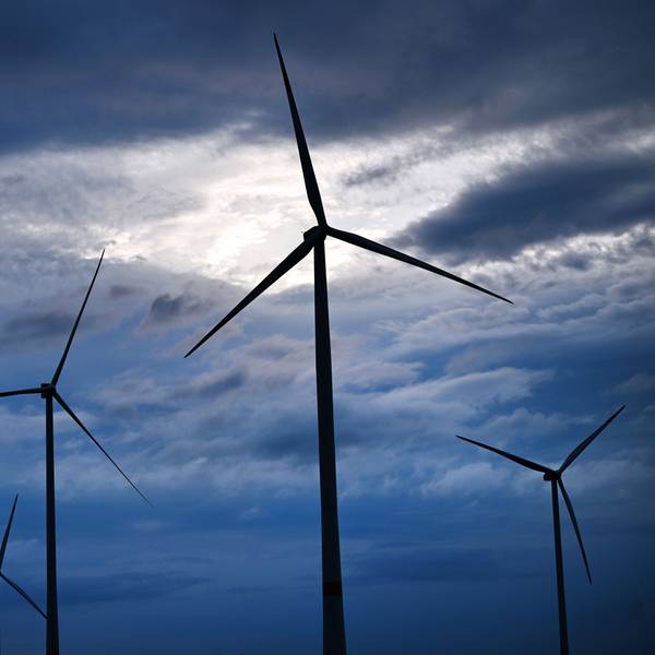Über einem Windpark bei Gotha scheint Sonnenlicht zwischen dunklen Regenwolken hindurch.