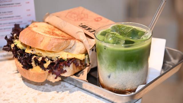Ein Sandwich und ein Iced-Matcha-Latte, serviert auf einem silbernen, eckigen Tablett
