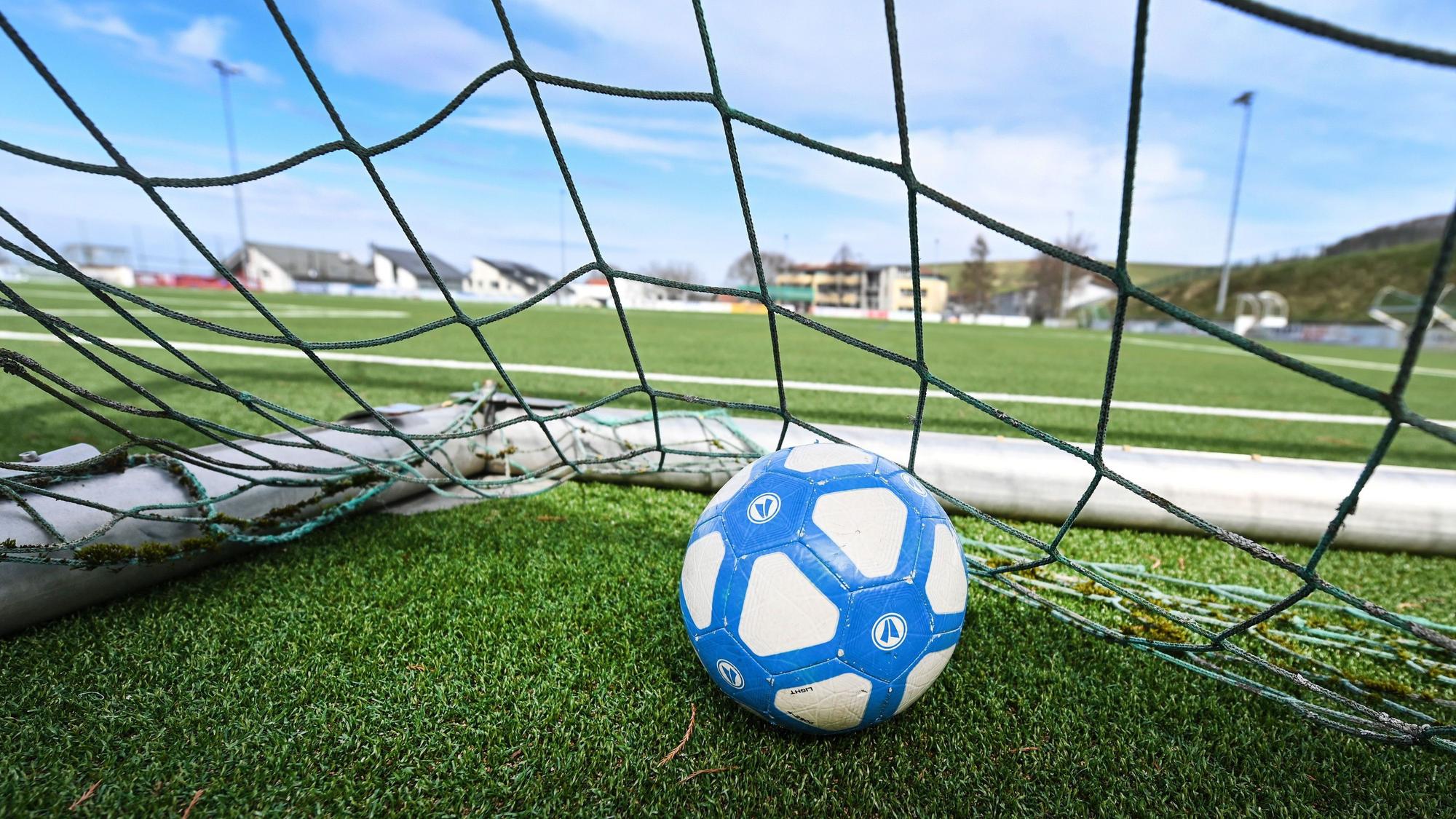 Ein Fußball liegt in einem Tor, das auf einem leeren Fußballplatz steht.
