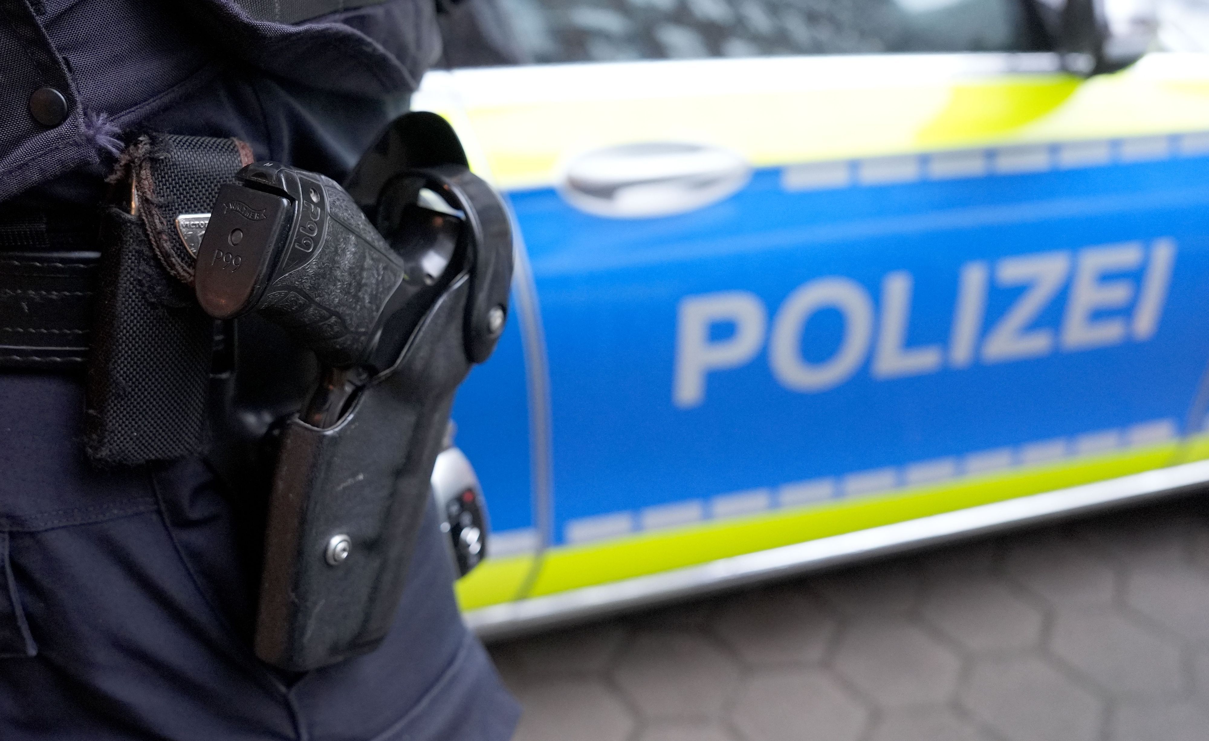 Ein Polizist steht vor einem Einsatzfahrzeug der Polizei