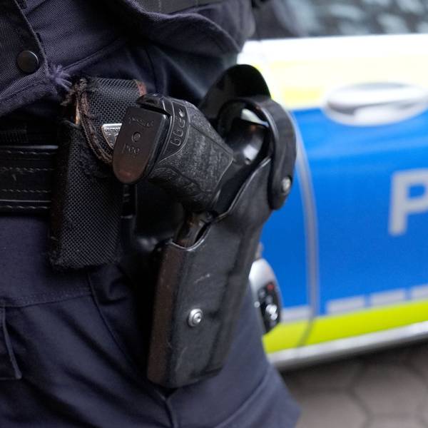 Ein Polizist steht vor einem Einsatzfahrzeug der Polizei.