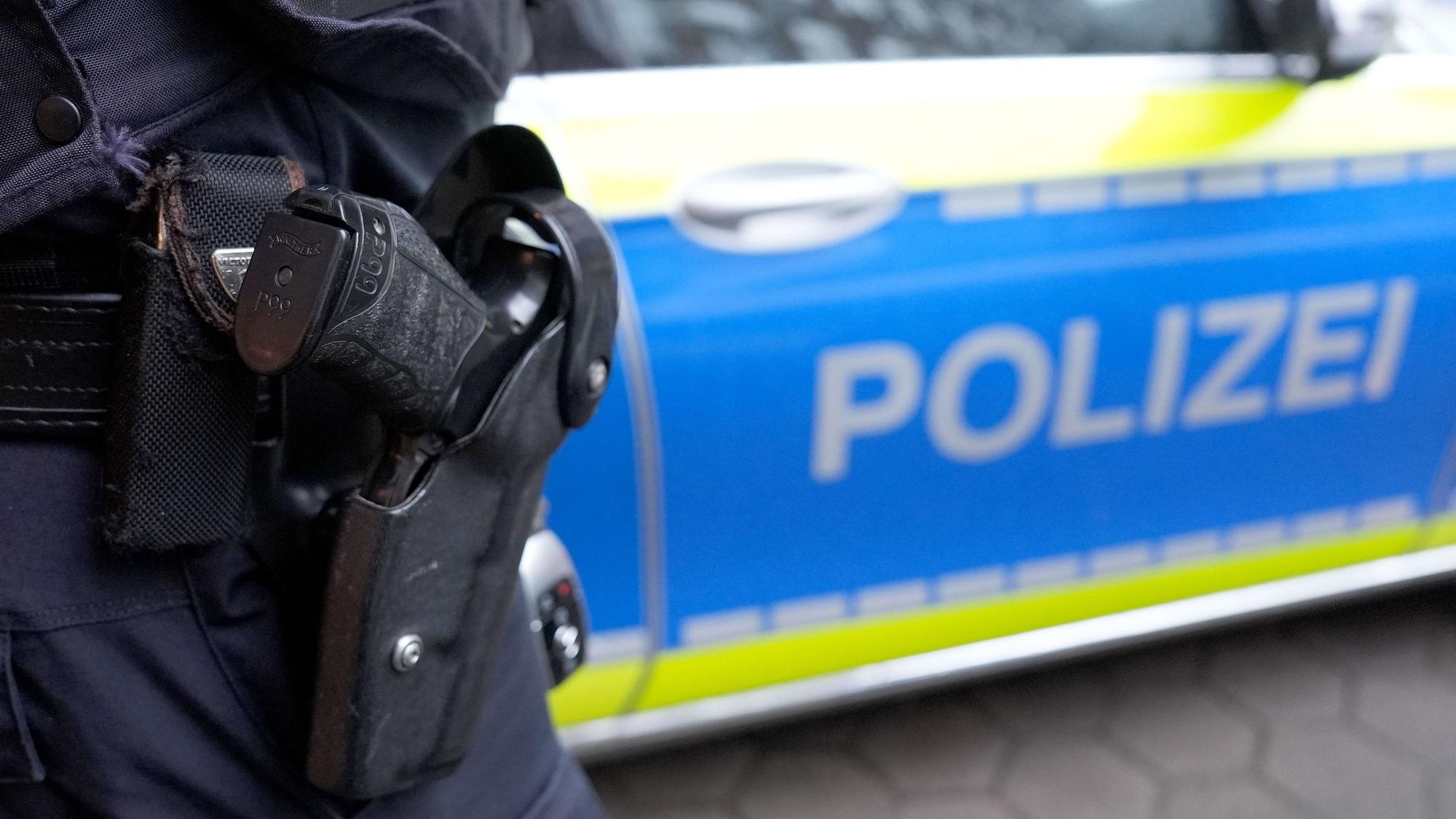 Ein Polizist steht vor einem Einsatzfahrzeug der Polizei