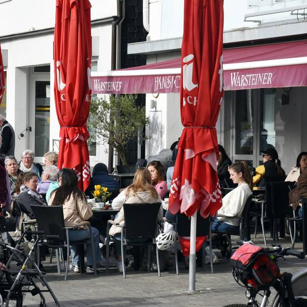 Das Foto zeigt Gäste an Tischen vor einer Gaststätte am Wipperfürther Marktplatz.