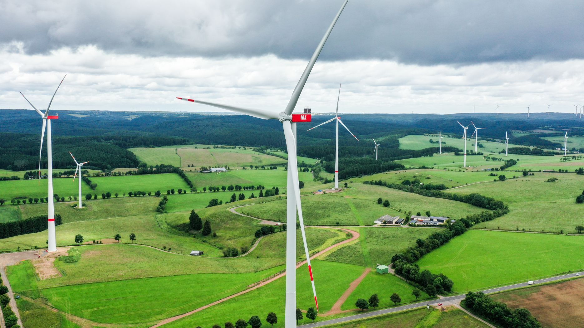 Mehrere Windräder stehen in der Eifellandschaft.