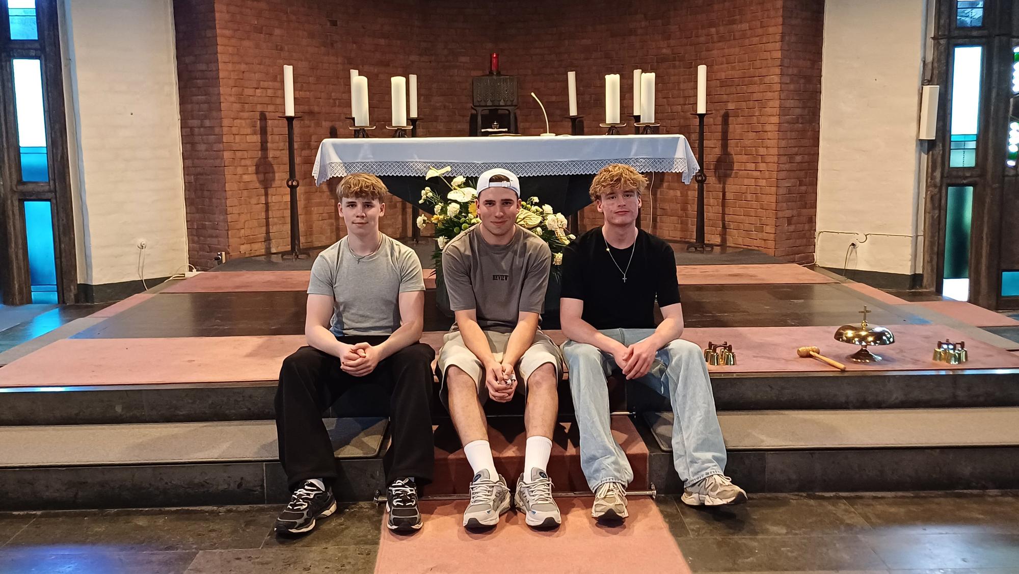 Niklas Kusber, Alexander Kusber und Hannes Wesselmann sitzen in einer Kirche.