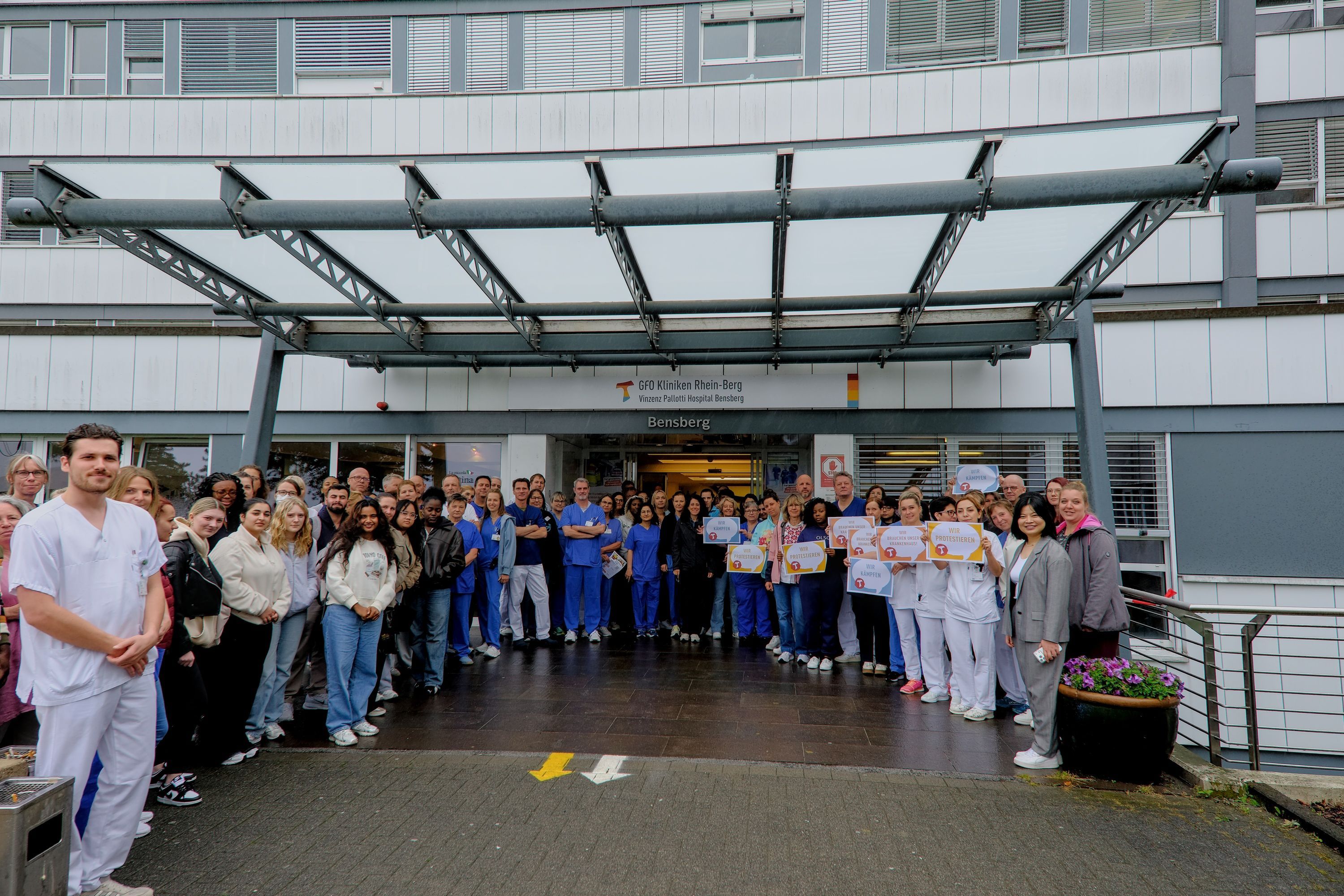 Beschäftigte aus Pflege und Ärzteschaft stehen vor dem Eingang des Vinzenz Pallotti Hospital.