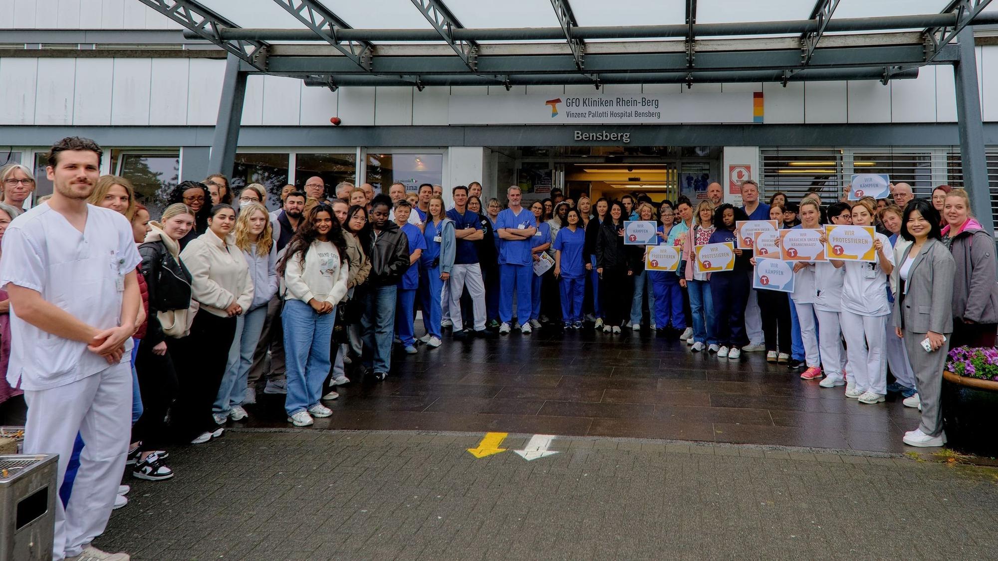 Beschäftigte aus Pflege und Ärzteschaft stehen vor dem Eingang des Vinzenz Pallotti Hospital.