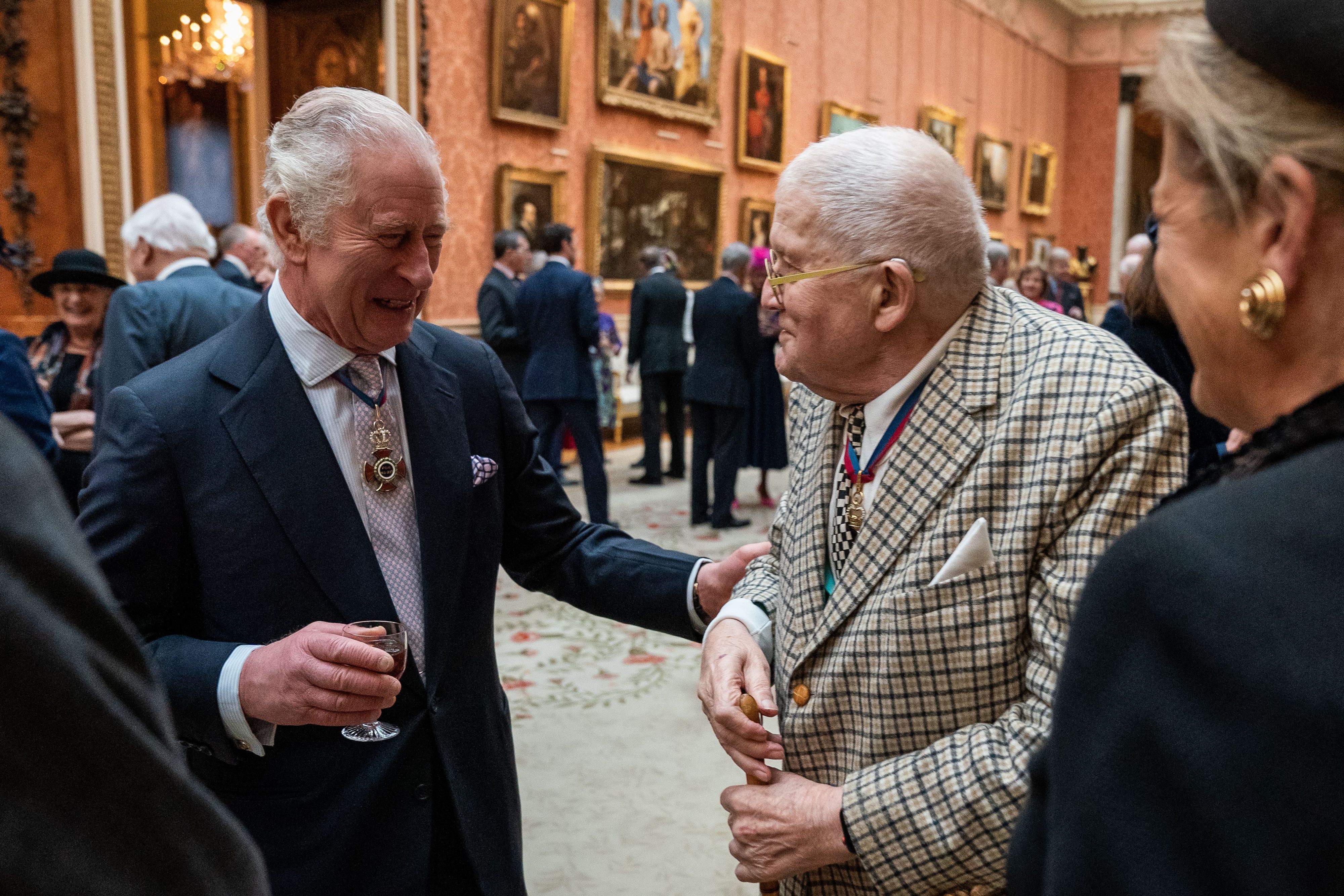 24.11.2022, Großbritannien, London: König Charles III. (l) im Gespräch mit David Hockney während eines Mittagessens für Mitglieder des Order of Merit im Buckingham Palace: Der legendäre britische Maler ist tot. Er starb im Alter von 88 Jahren «friedlich zu Hause», wie die Nachrichtenagentur PA unter Berufung auf seinen Publizisten mitteilte.