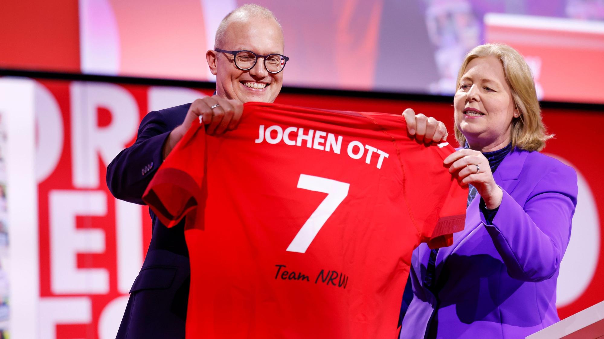 Bärbel Bas (SPD), Bundesministerin für Arbeit und Soziales, überreicht Jochen Ott bei der Landesdelegiertenkonferenz der SPD in Nordrhein-Westfalen nach der Wahl zum Spitzenkandidaten für die Landtagswahl 2027 ein Trikot mit der Aufschrift: „Jochen Ott 7 Team NRW“.