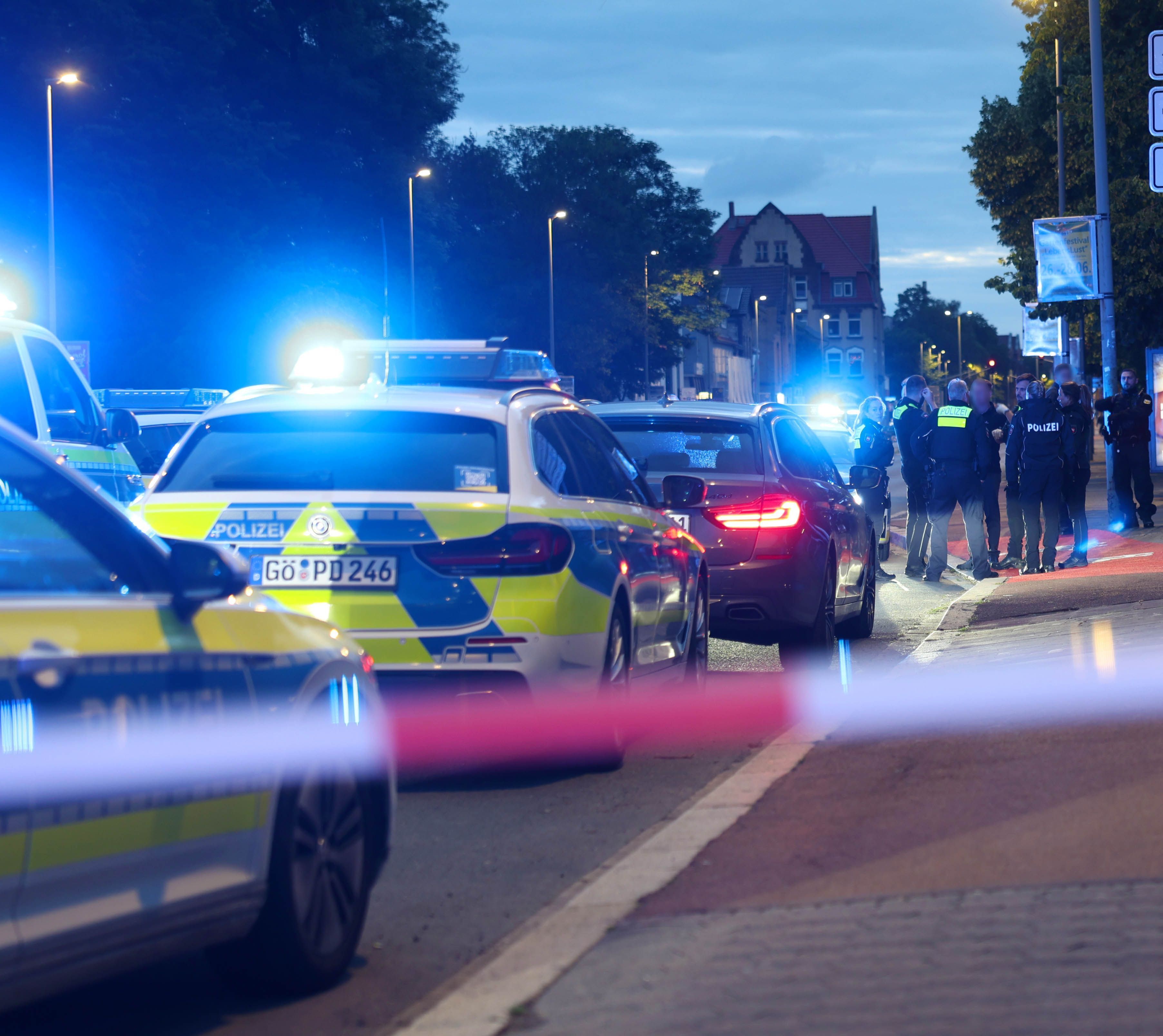 Polizisten und Polizeifahrzeuge stehen hinter einer Absperrung. Ein Polizist ist bei einer Auseinandersetzung zwischen zwei Personengruppen im niedersächsischen Göttingen angeschossen worden.