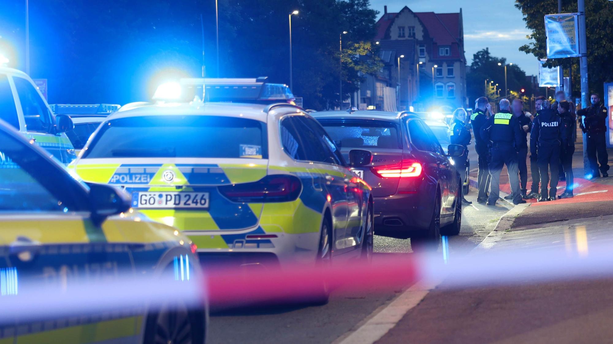 Polizisten und Polizeifahrzeuge stehen hinter einer Absperrung. Ein Polizist ist bei einer Auseinandersetzung zwischen zwei Personengruppen im niedersächsischen Göttingen angeschossen worden.