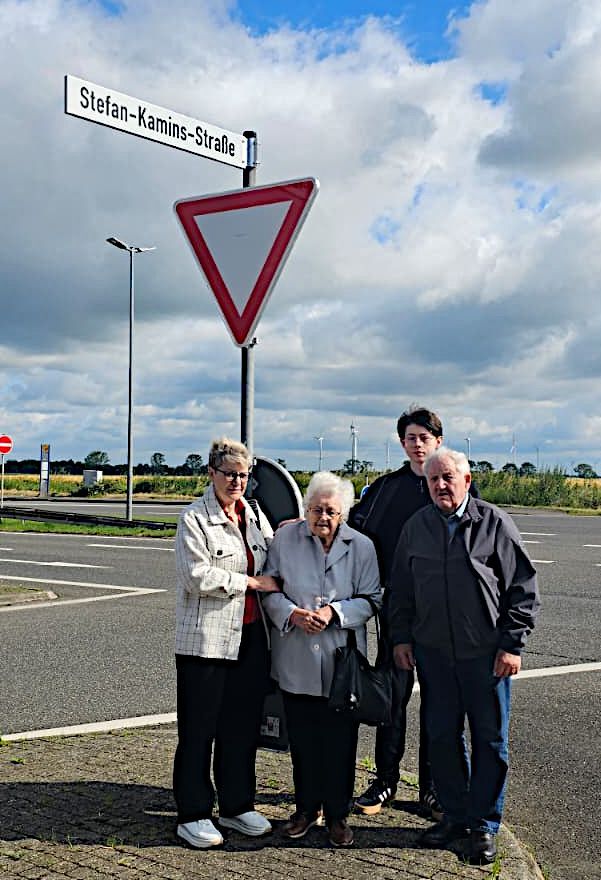 Zwei Frauen und zwei Männer stehen aneiner Kreuzung unter einem Straßenschild.