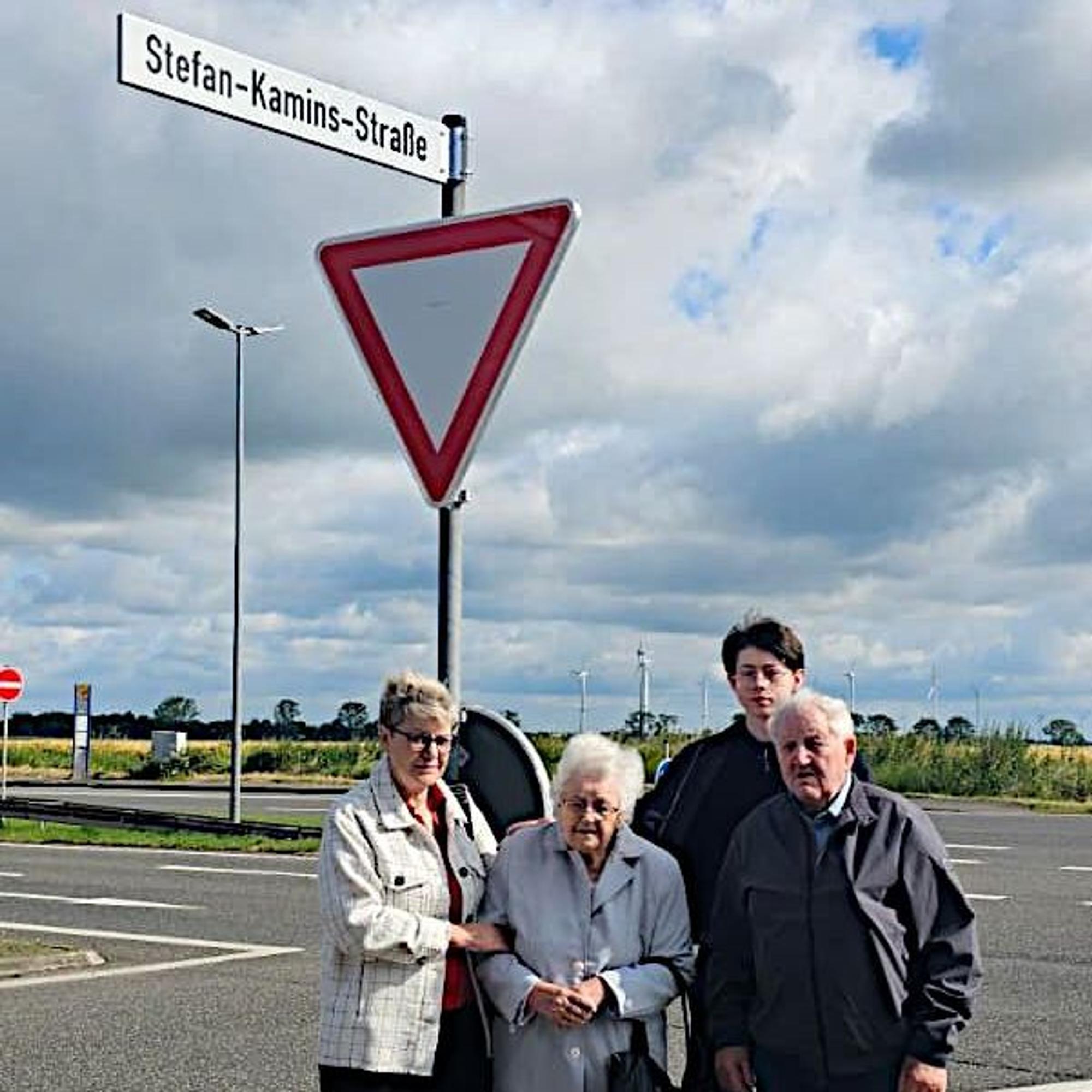 Zwei Frauen und zwei Männer stehen aneiner Kreuzung unter einem Straßenschild.