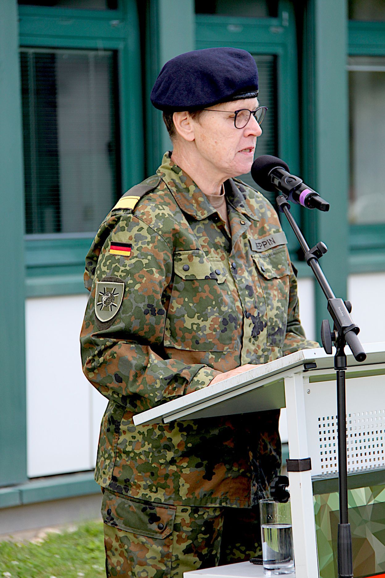 Standortälteste Sabine Reppin steht in Uniform an einem Pult und spricht in ein MIkrofon