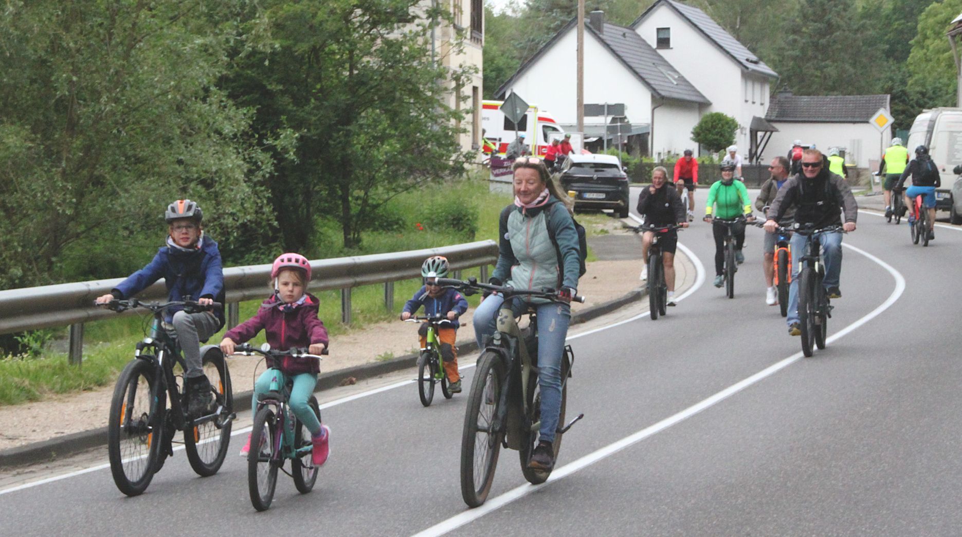 Kinder und Erwachsene fahren mit dem Fahrrad über eine Straße.