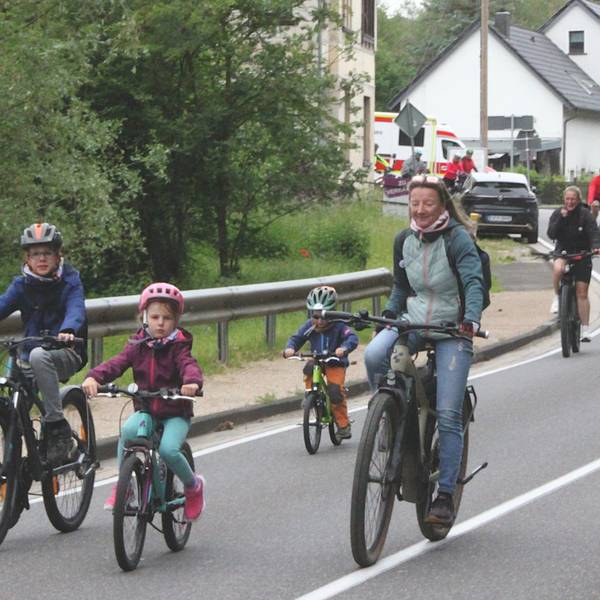 Kinder und Erwachsene fahren mit dem Fahrrad über eine Straße.