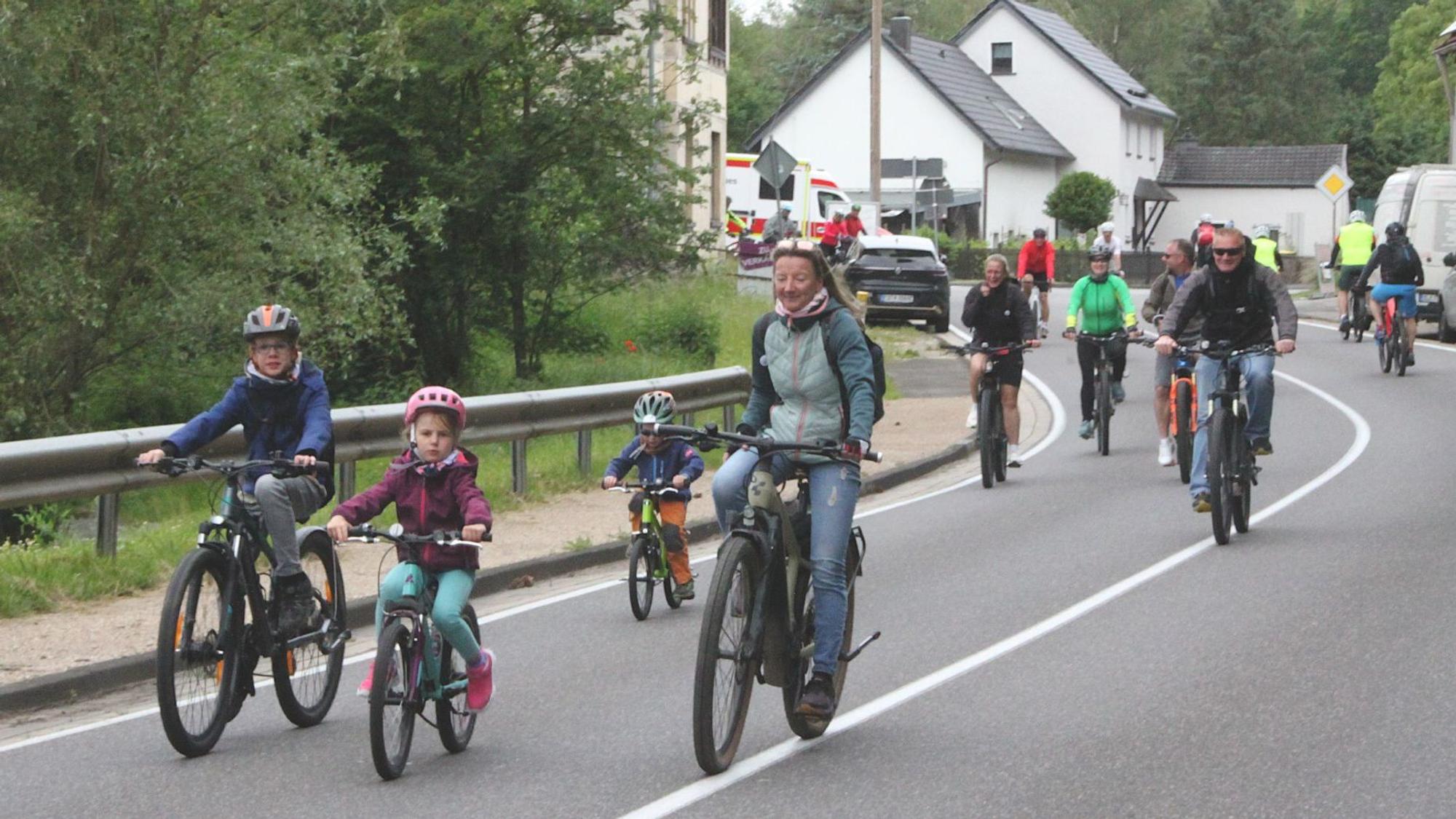 Kinder und Erwachsene fahren mit dem Fahrrad über eine Straße.