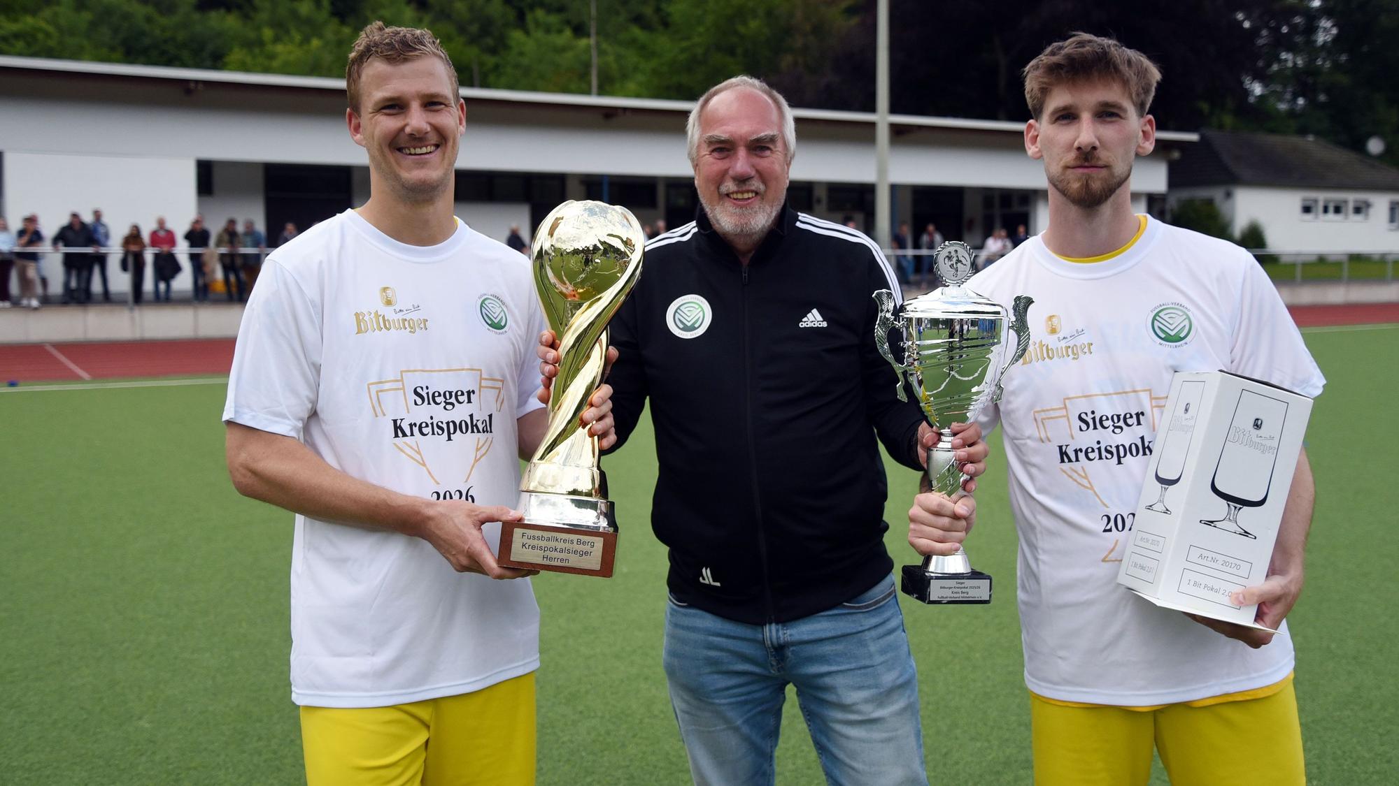 Pokalübergabe eines Offiziellen an zwei Fußballspieler
