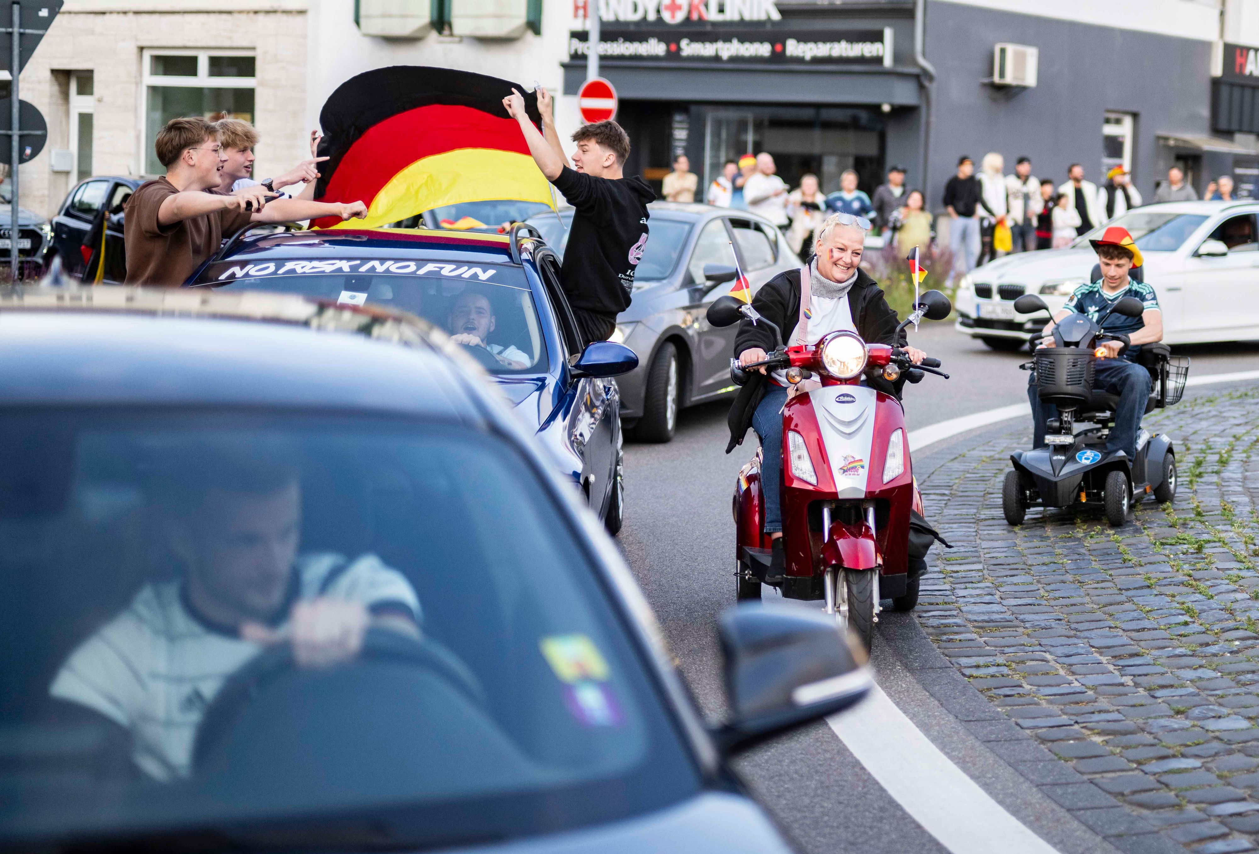 Eine Frau und ein junger Mann fahren mit Elektromobilen am Autokorso vorbei.
