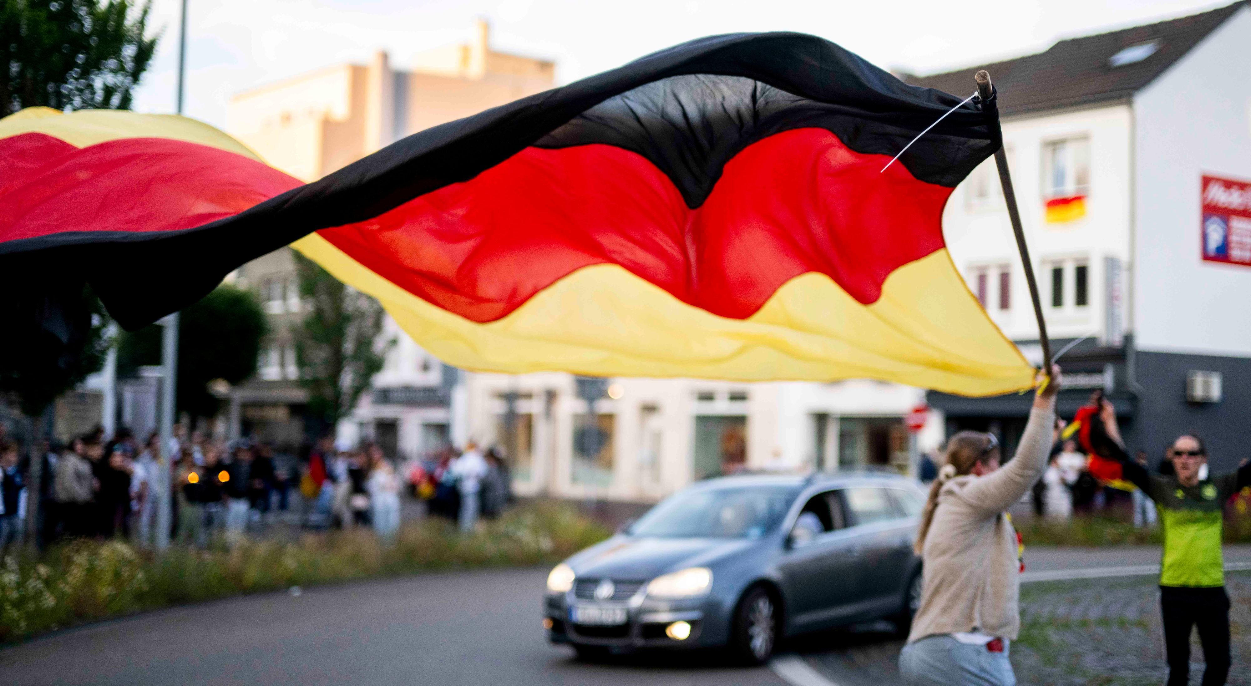 Eine Frau läuft mit einer riesiegen Deutschland-Fahne durch den Kreisel.