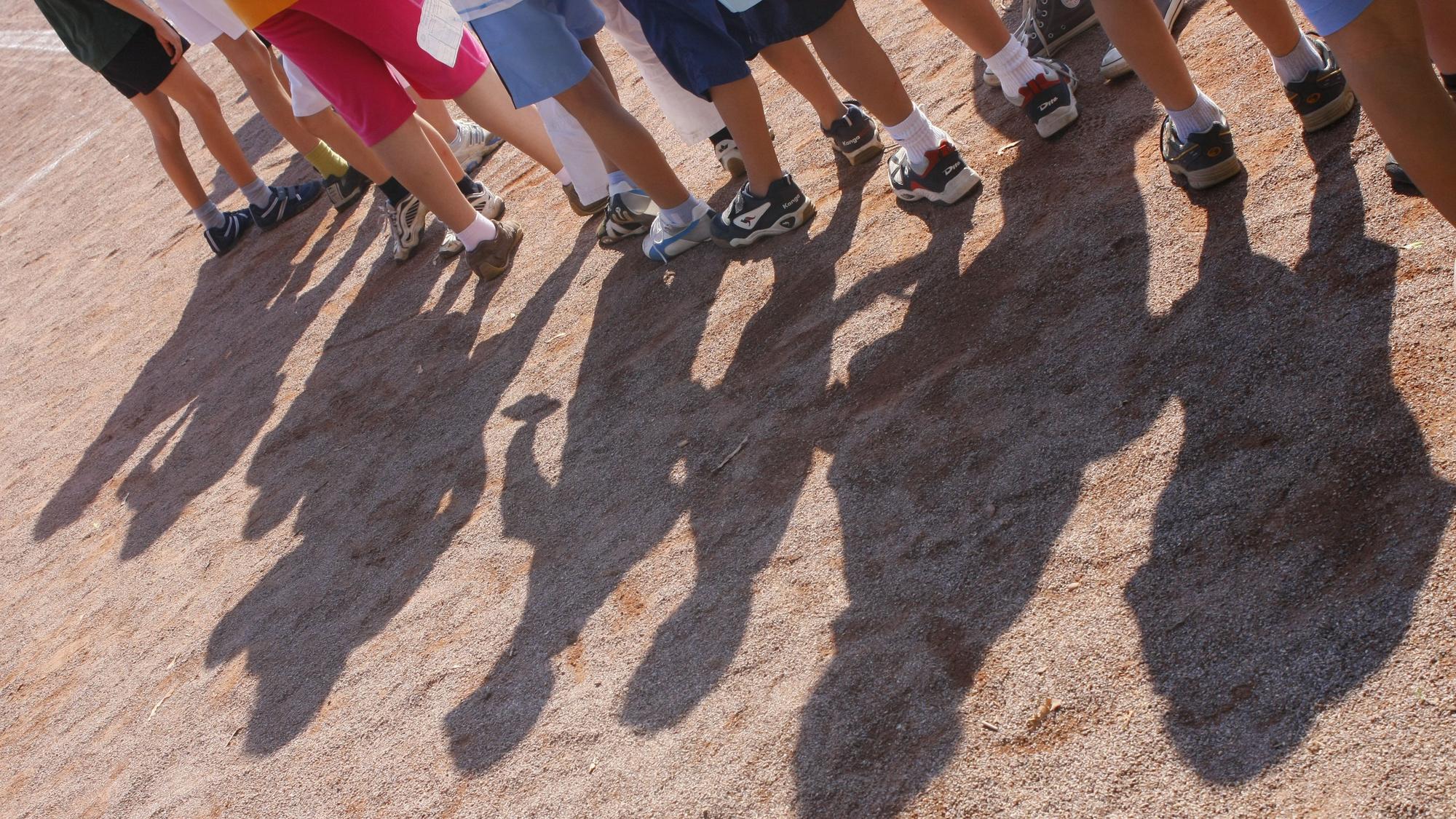 Kinder einer Grundschule stehen im Rahmen der Bundesjugendspiele auf einem Sportplatz. (Archivbild)
