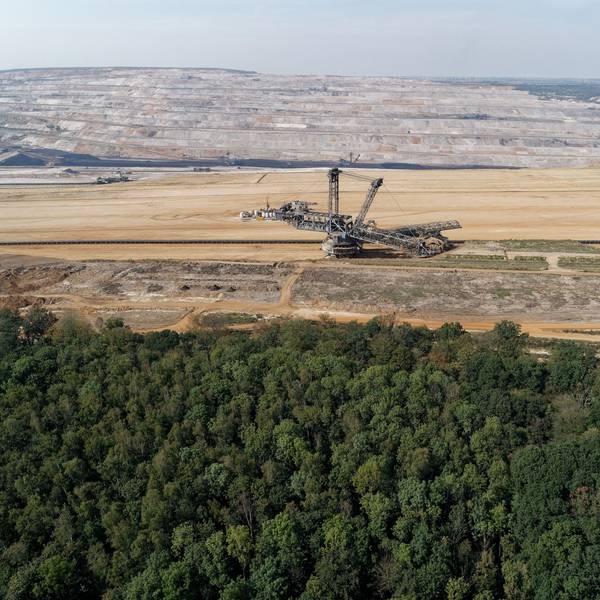 Das Foto zeigt den Tagebau Hambach mit einem Bagger, davor der Hambacher Forst.