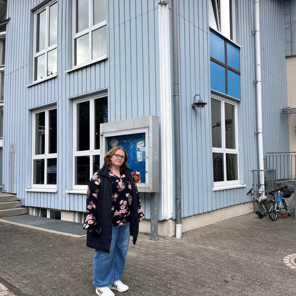 Die Mutter steht vor dem OGS-Gebäude.