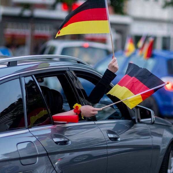 Aus einem Auto im Autokorso nach dem WM-Auftaktsieg wird mit zwei Deutschland-Fähnchen gewunken.