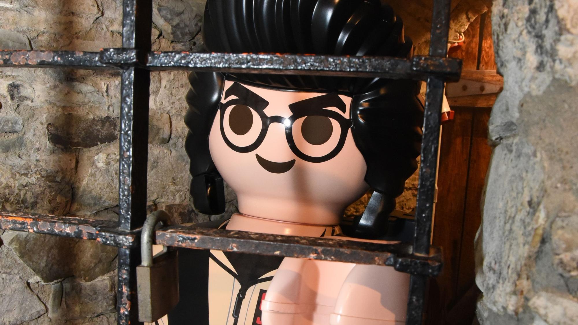 Eine große Playmobil-Figur hinter Gittern.