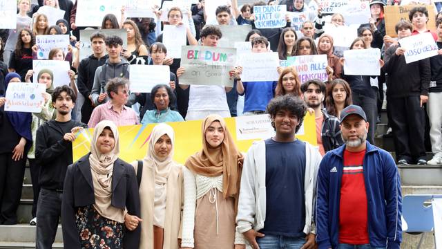 Familie Rouf aus Sri Lanka, dahinter Schüler mit Plakaten