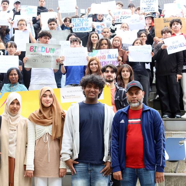 Familie Rouf aus Sri Lanka, dahinter Schüler mit Plakaten