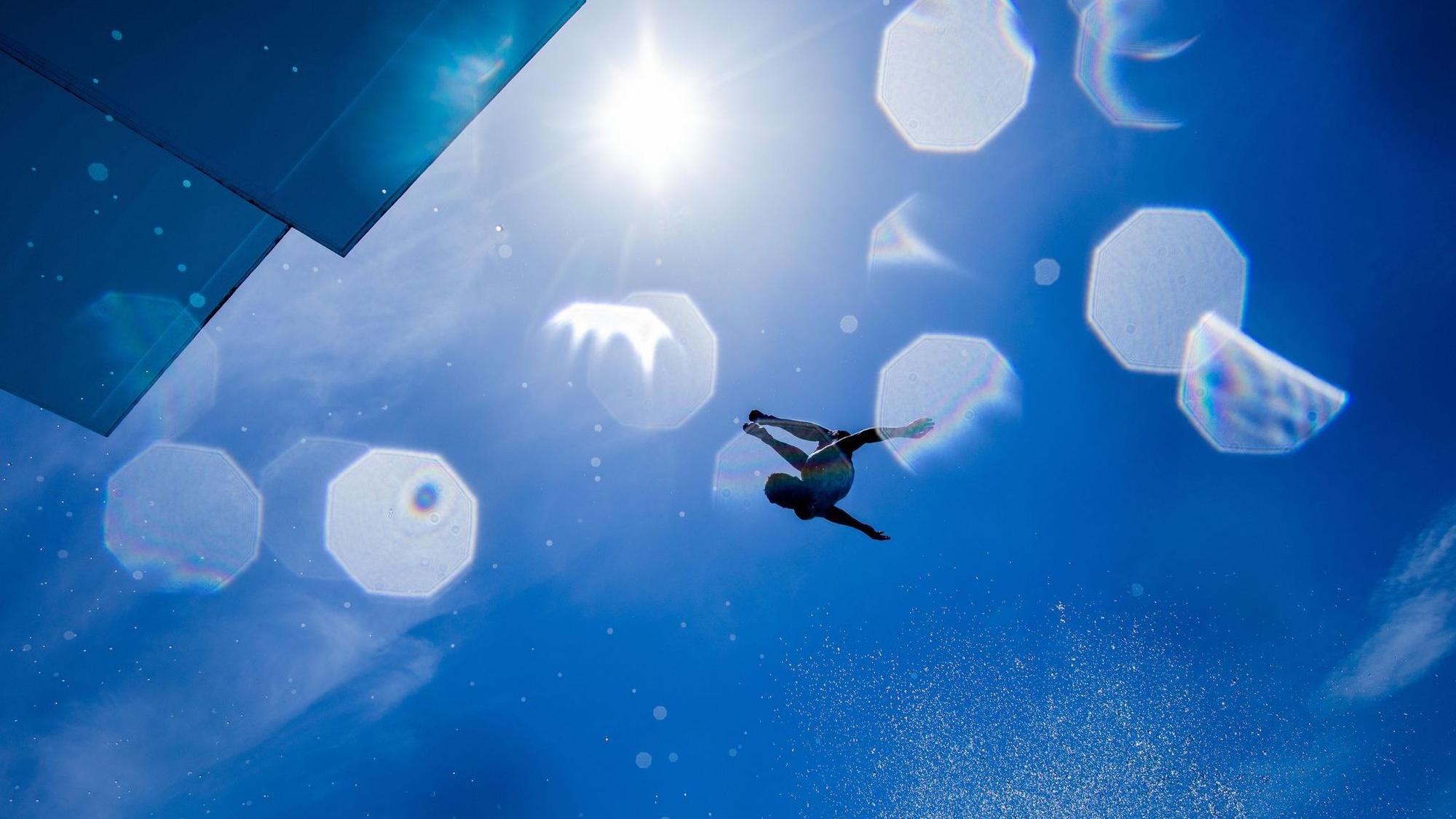 Mann springt von Sprungturm eines Freibads