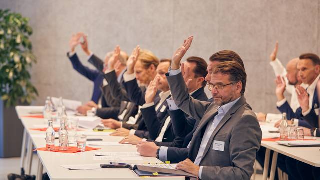 Die Vertreter der an der Initiative beteiligten Unternehmen signalisieren mit erhobenen Händen ihre Zustimmung zur Satzung