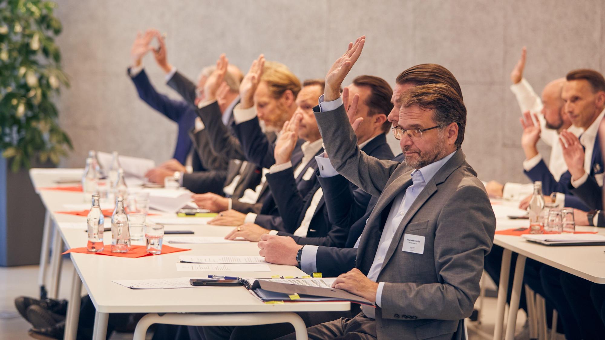 Die Vertreter der an der Initiative beteiligten Unternehmen signalisieren mit erhobenen Händen ihre Zustimmung zur Satzung