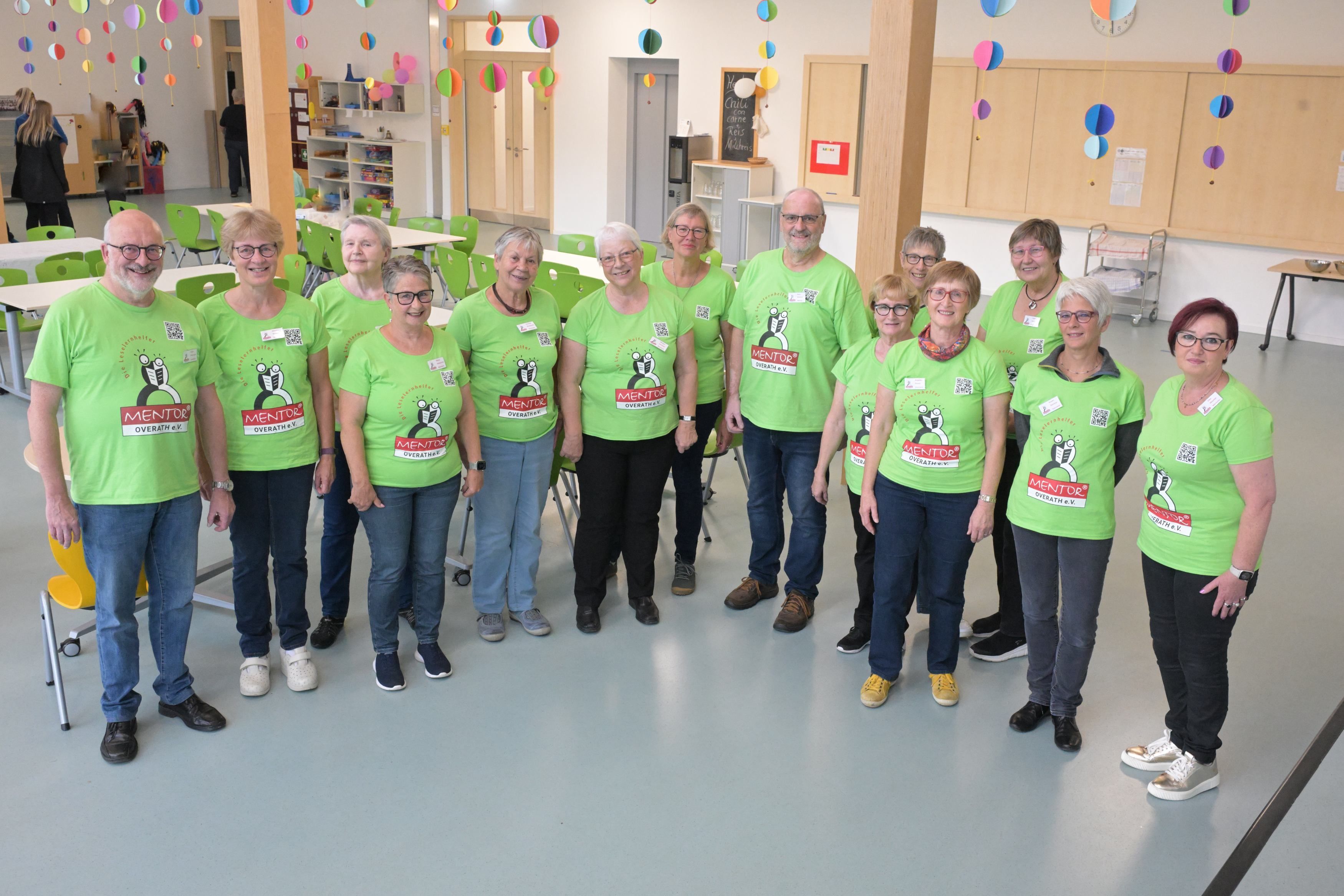 Eine Gruppe von Männern und Frauen steht zusammen mit einheitlichen T-Shirts und schaut in eine Kamera.