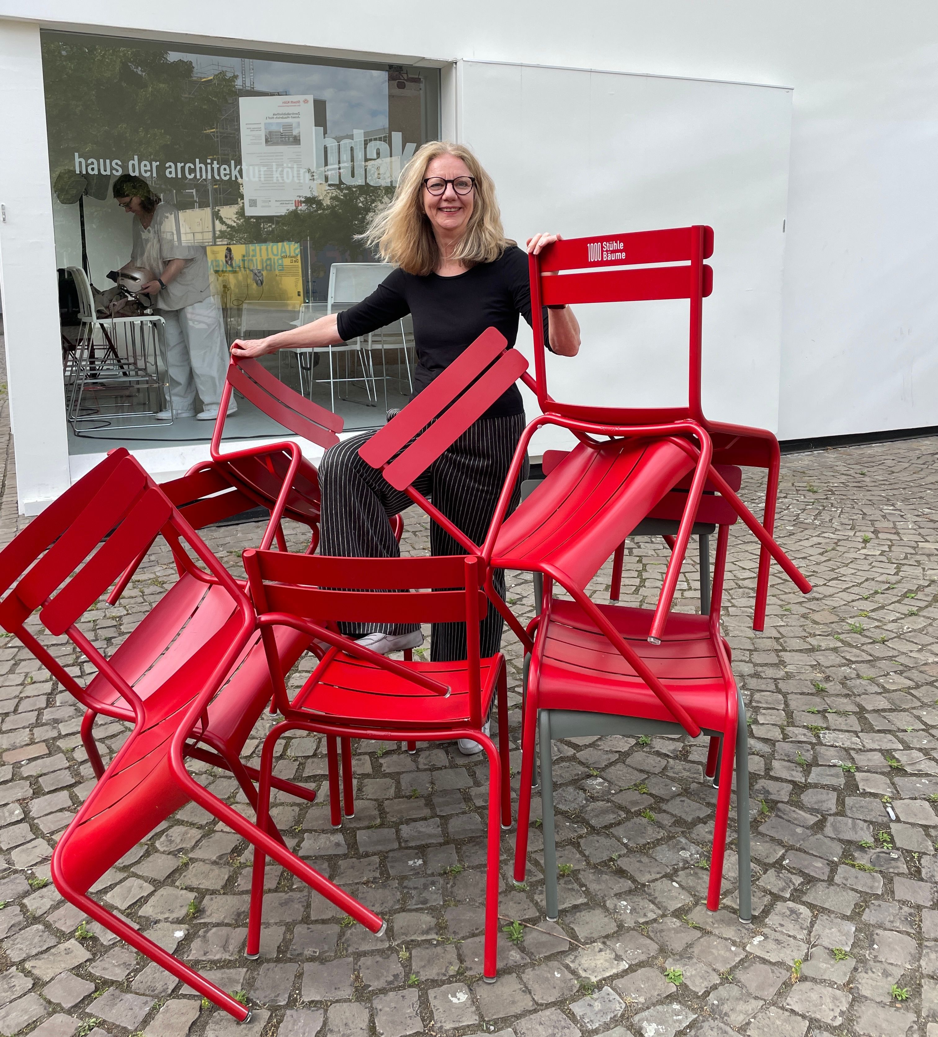 Dörte Gatermann, Vorsitzende Haus der Architektur Köln (hdak) vor dem Kubus auf dem Josef Haburich Hof mit den roten Stühlen